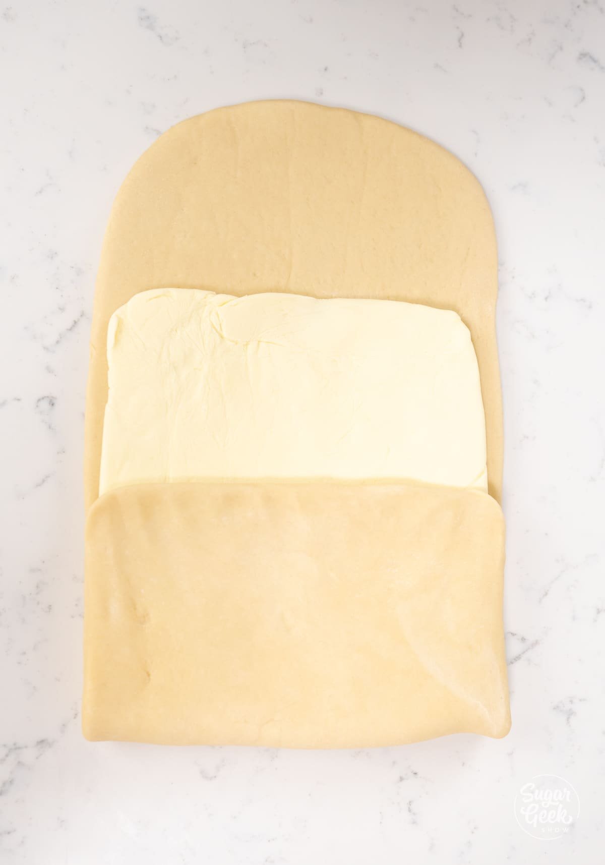 half a rectangle of croissant dough folded over half of a butter square