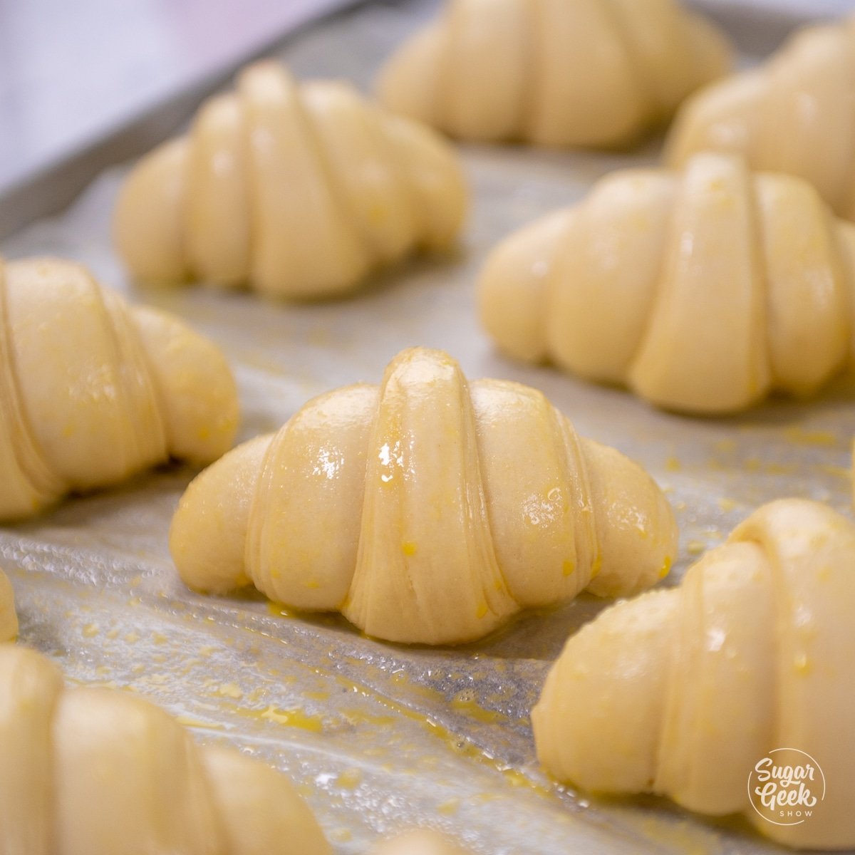 croissants covered in egg wash on a baking sheet