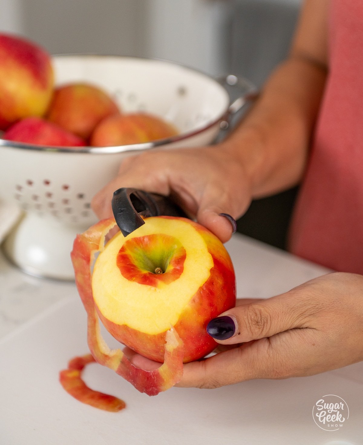 hands peeling an apple. 