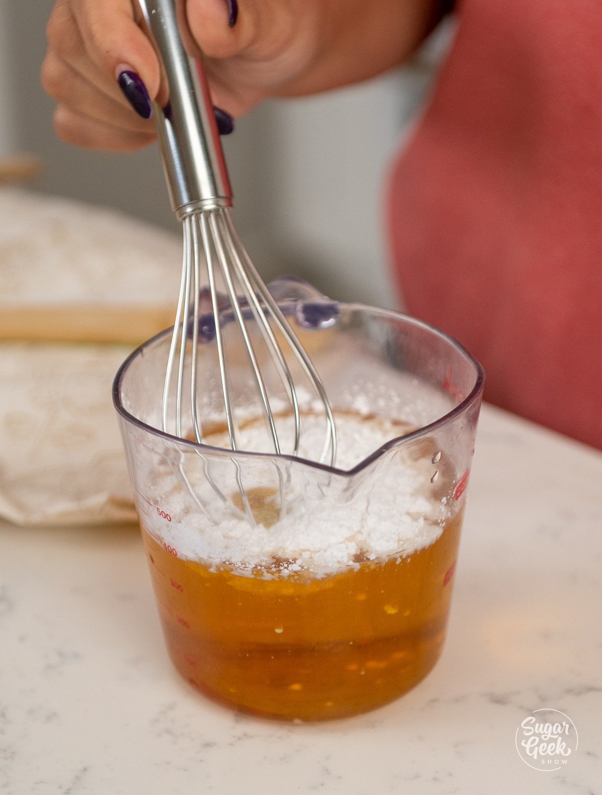 combining apple juice with corn starch in a measuring cup with a whisk. 