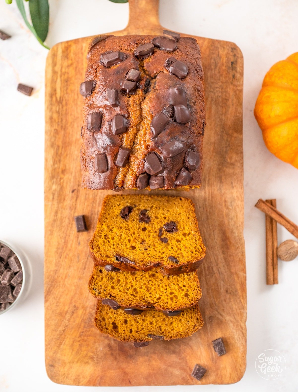 three slices of pumpkin bread laying down next to a loaf on top of a wooden board 