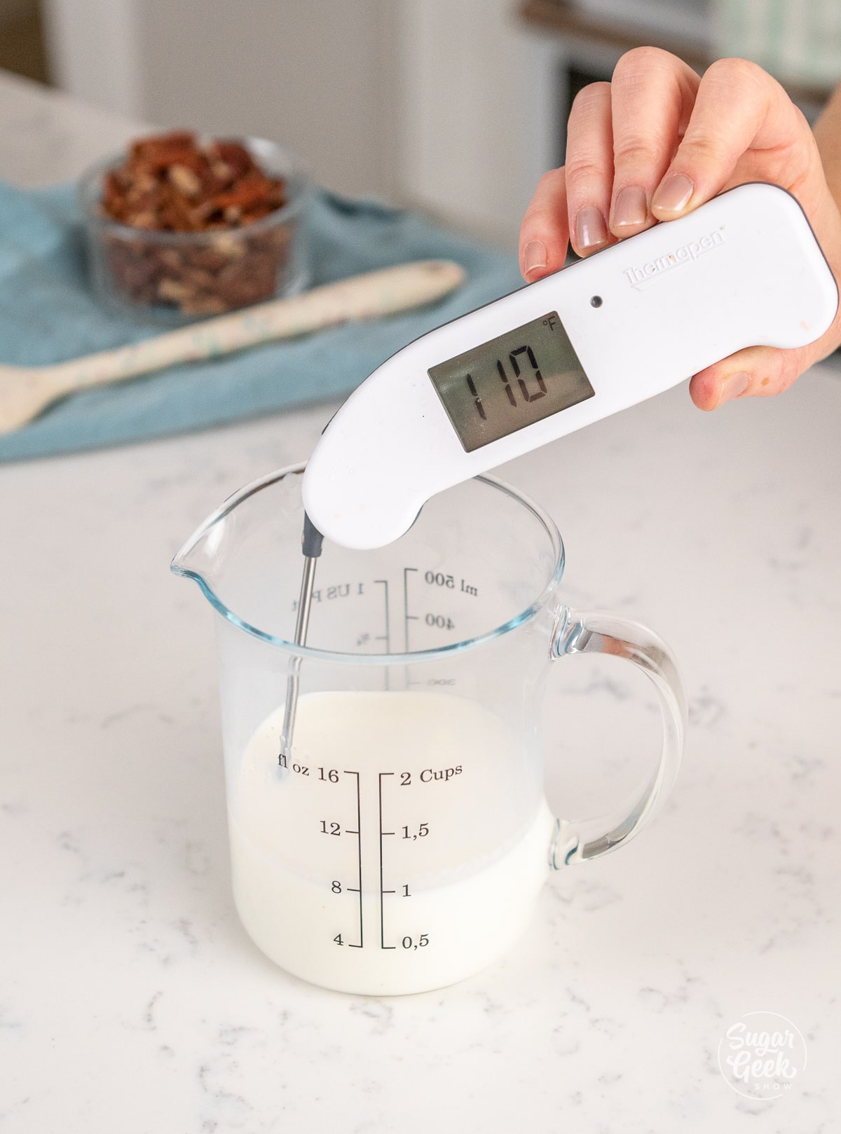 hand holding a thermometer in a container of milk reading 110 degrees