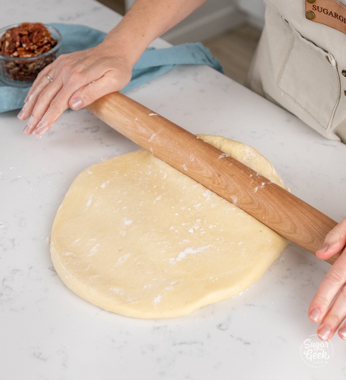 hands rolling out dough with a wooden rolling pin