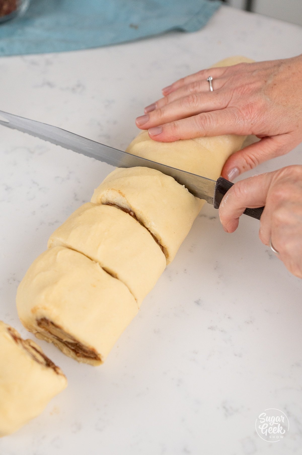serrated knife cutting through a log of dough