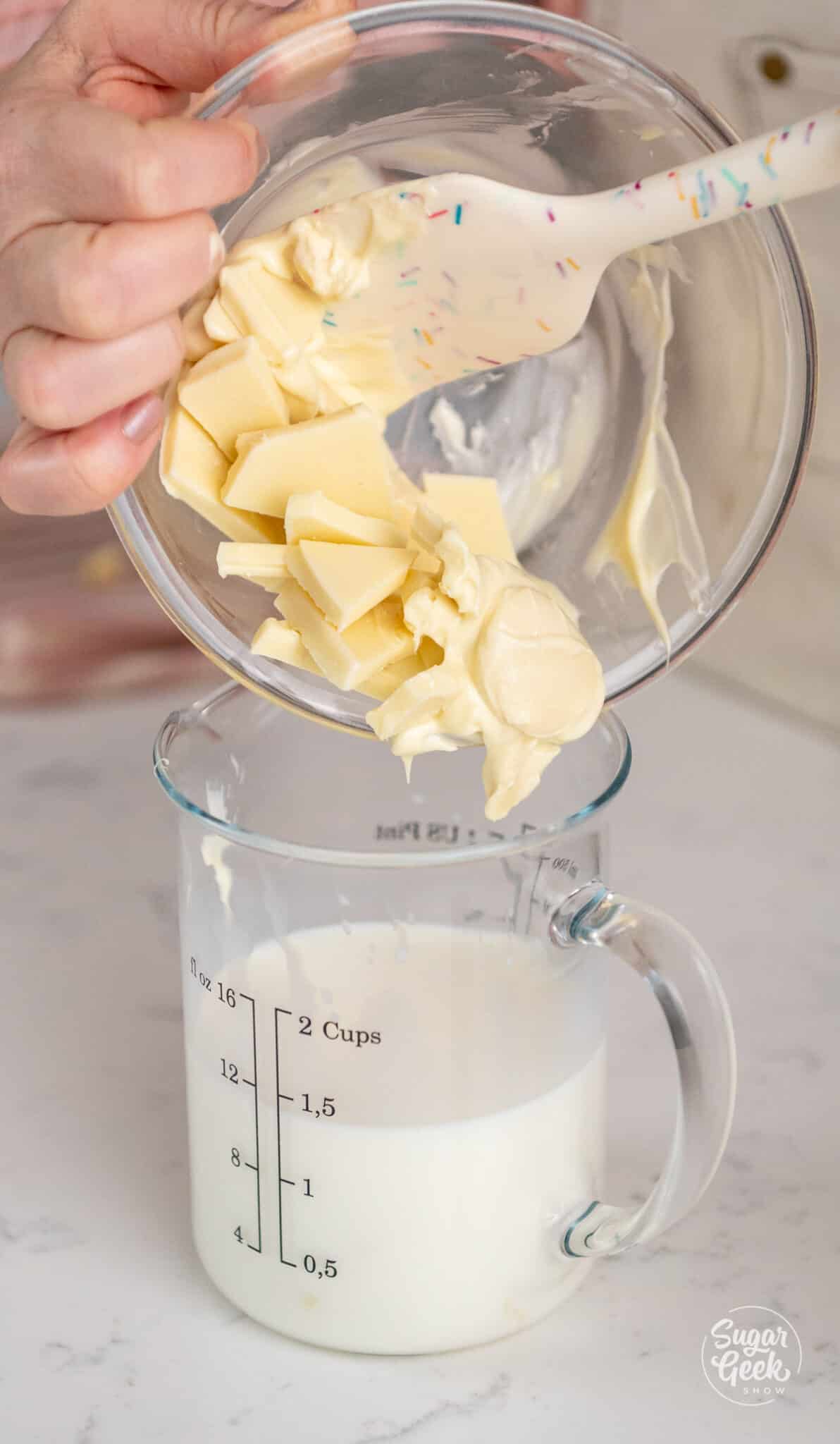 hands pouring a bowl of white chocolate into a container of milk