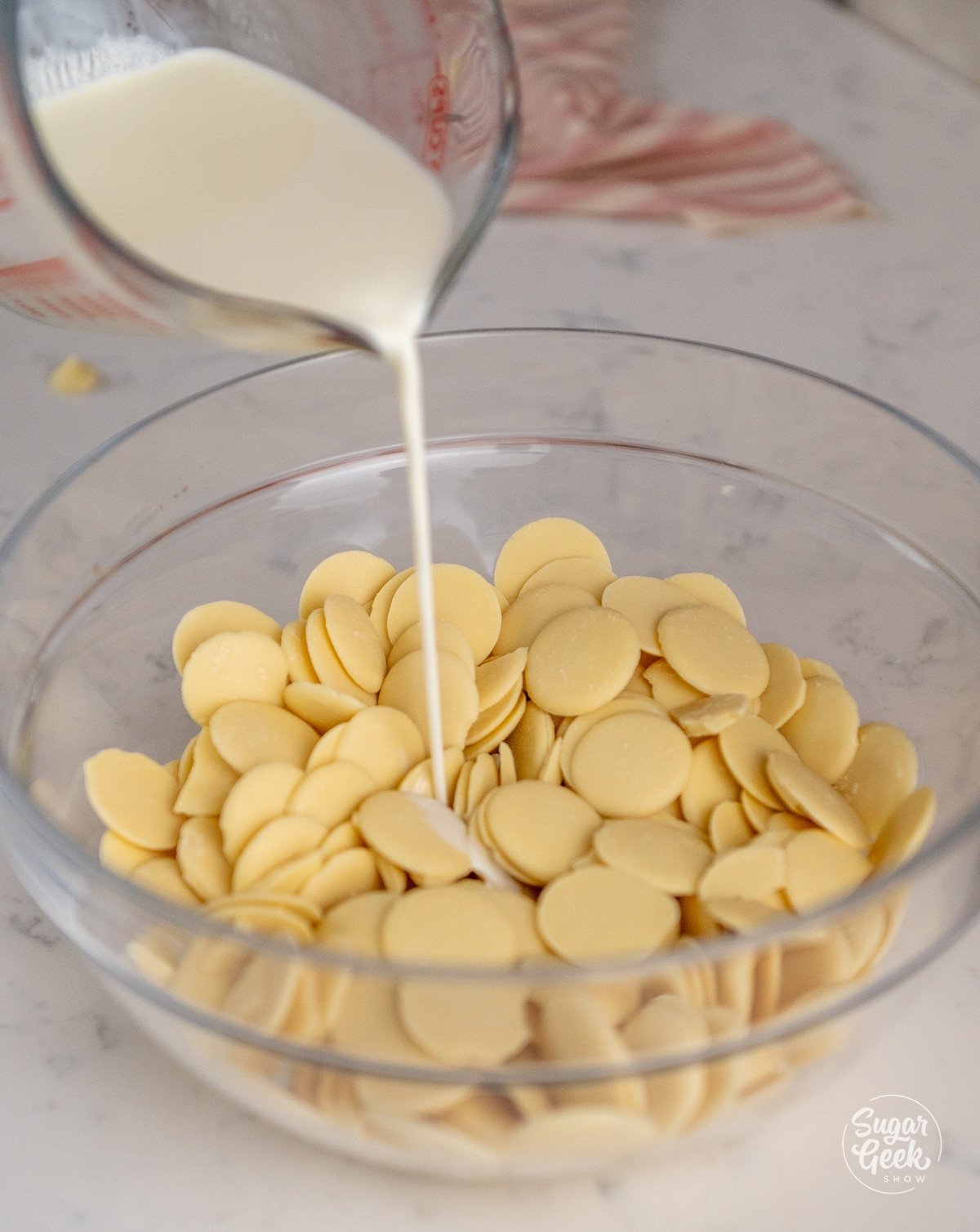 heavy cream pouring into a bowl of white chocolate
