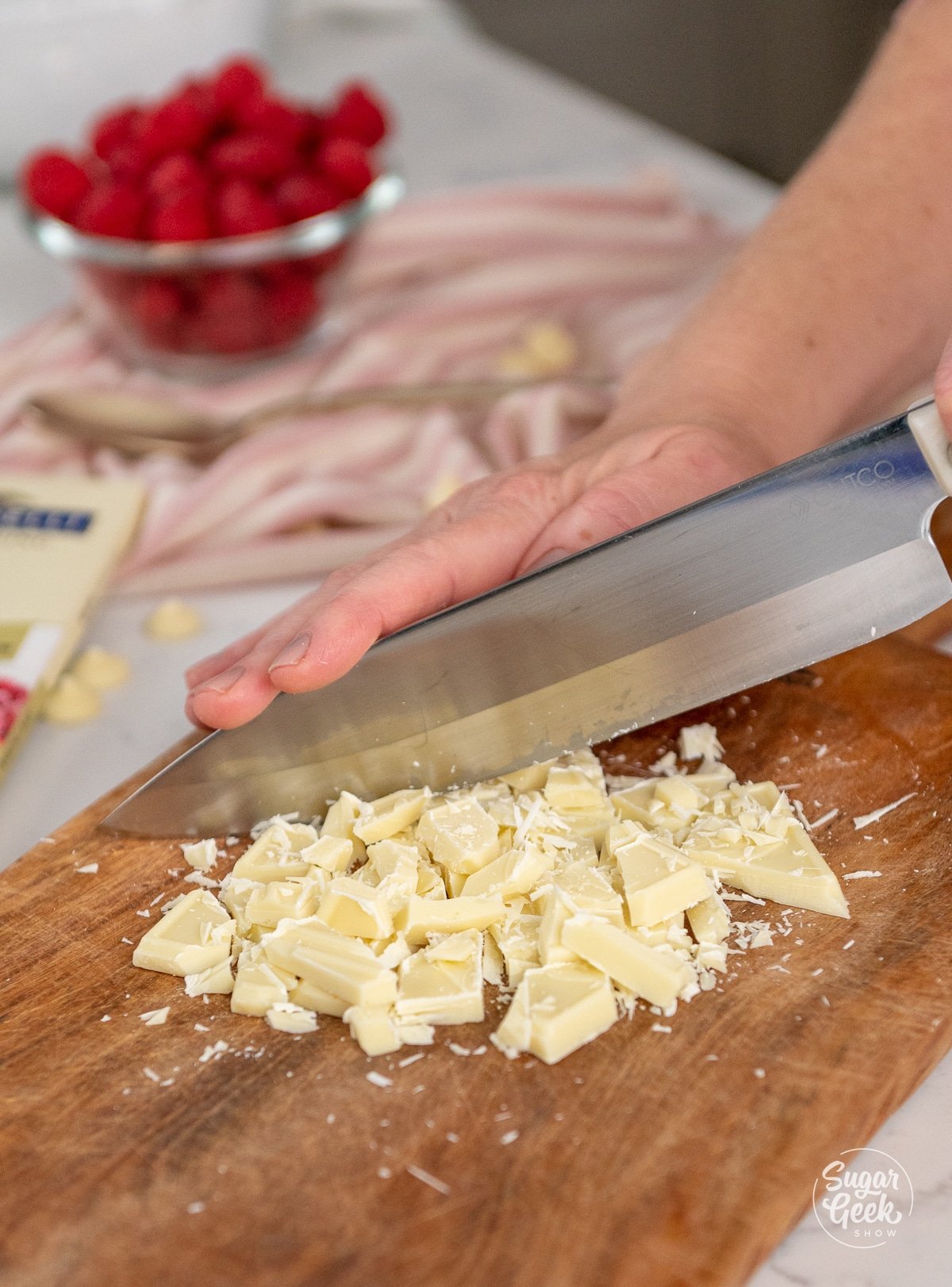 hand chopping white chocolate with a knife.