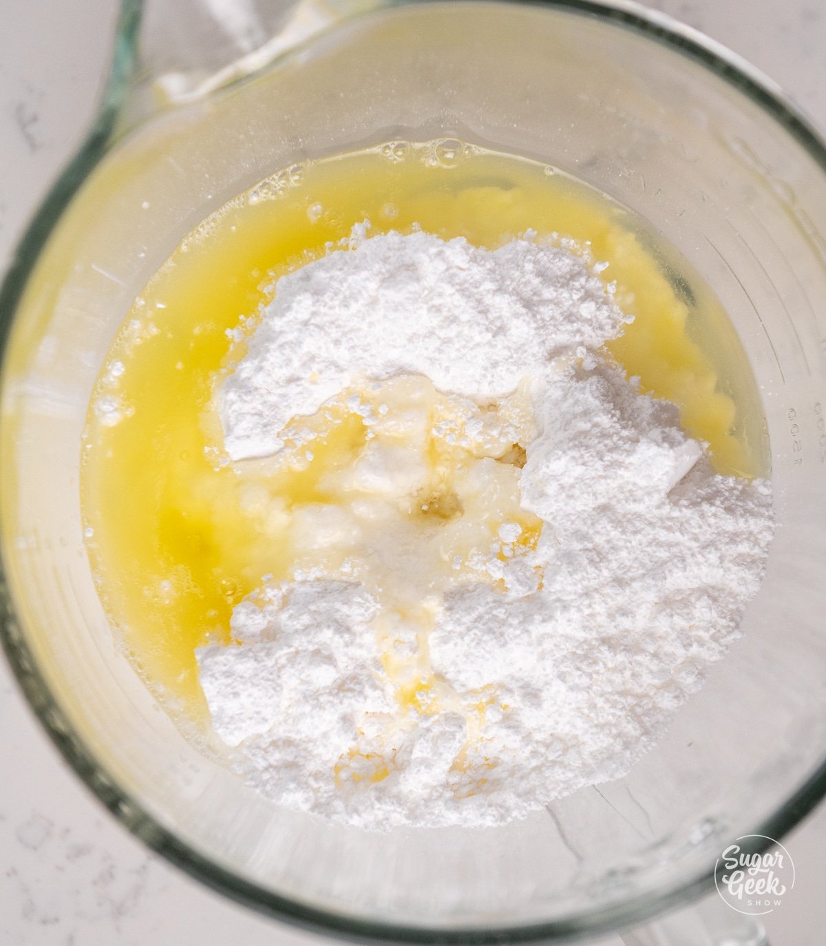 egg whites and powdered sugar in a glass bowl.