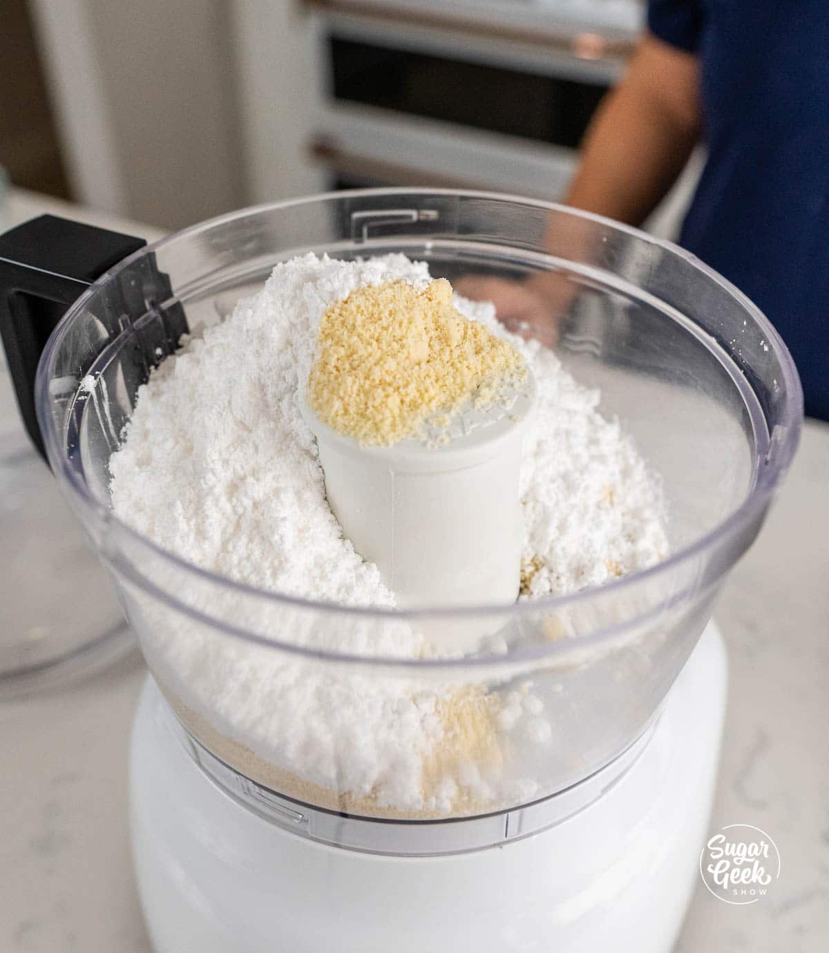 close up of powdered sugar and almond flour in a food processor