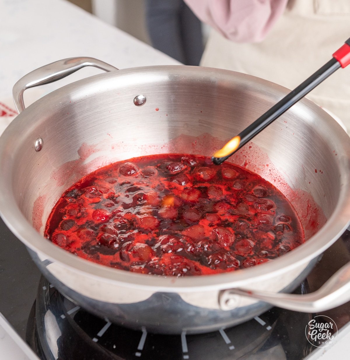 long lighter flambéing cherries in a pan