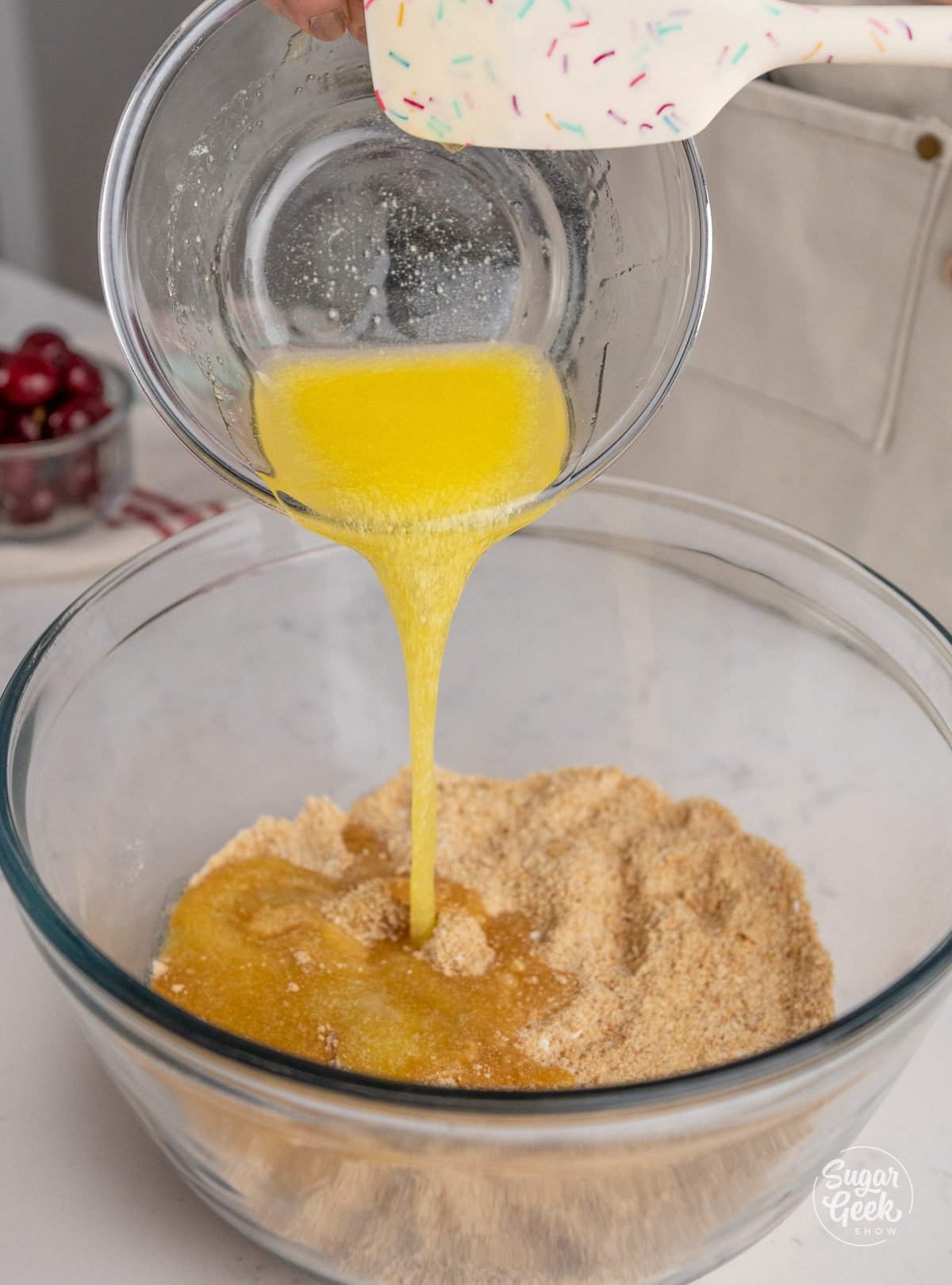 melted butter pouring into a bowl of graham cracker crust ingredients