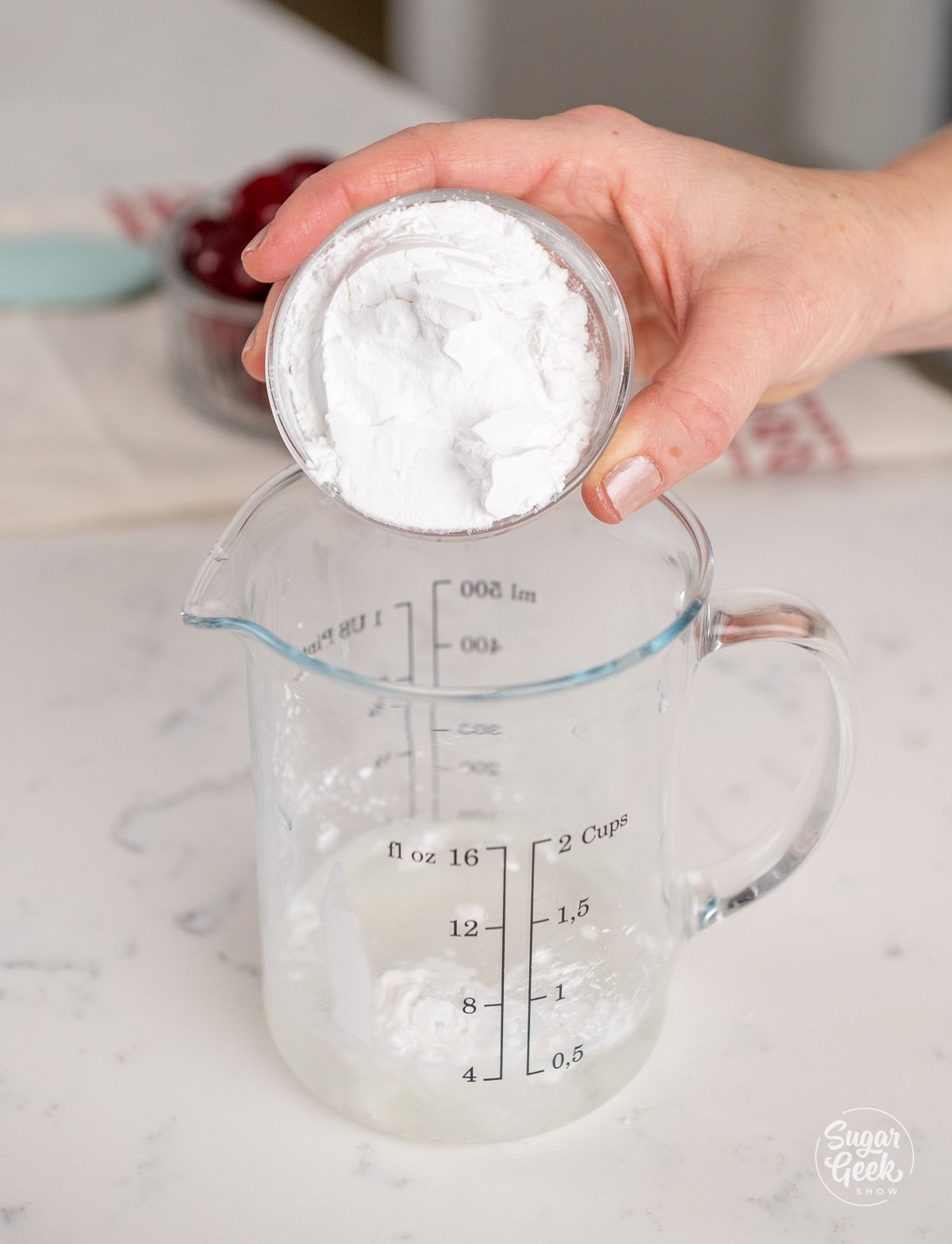 hand adding a bowl of cornstarch to a measuring cup