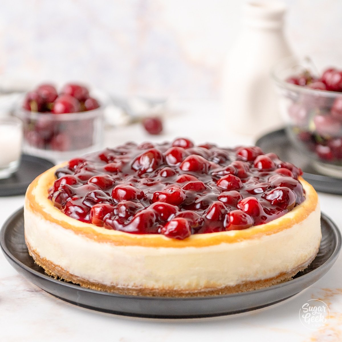 A cheesecake with cherry topping on a black plate