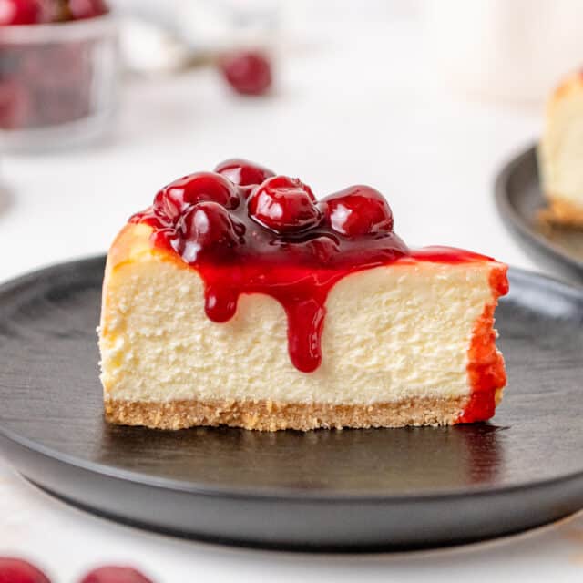 slice of cherry cheesecake on a black plate