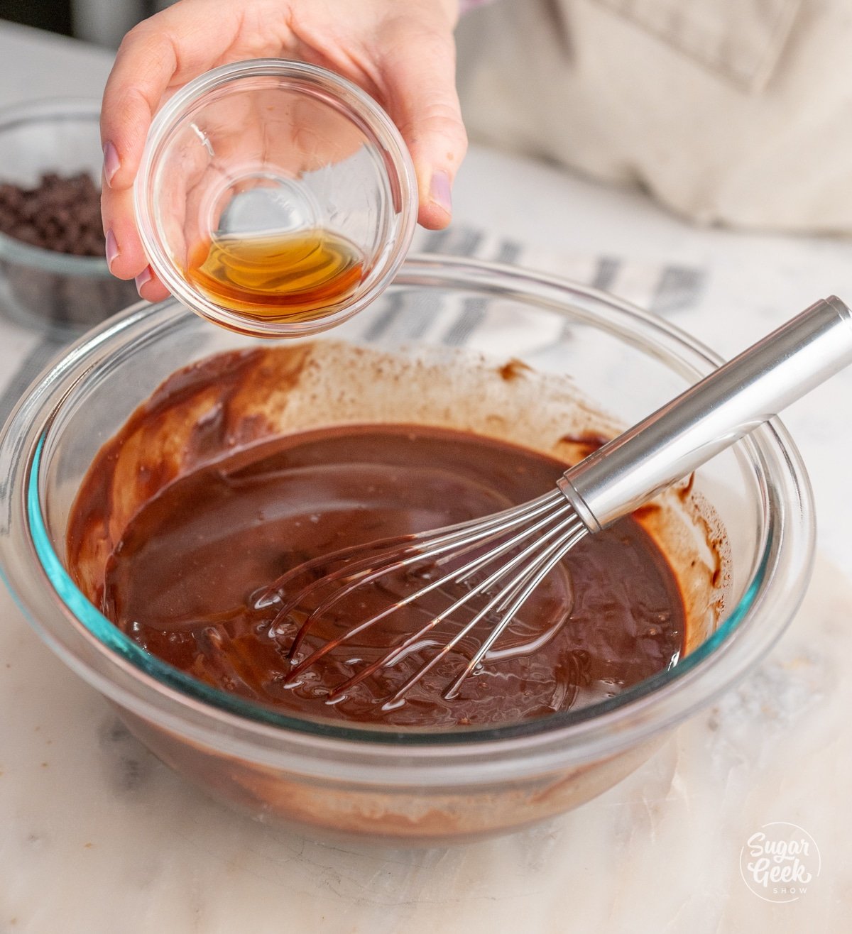 hand pouring a bowl of vanilla into a bowl of ganache