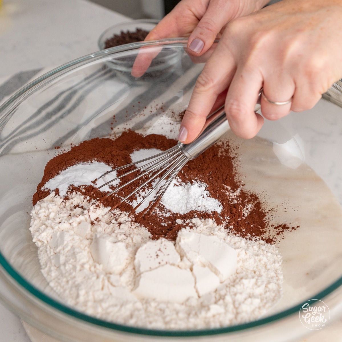 hand whisking dry ingredients in a glass bowl