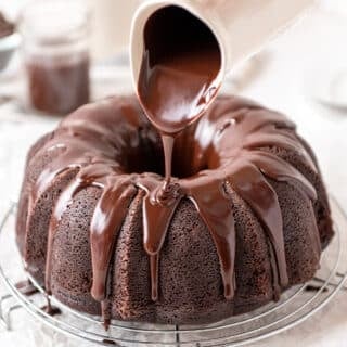 chocolate glaze pouring from a container onto a chocolate bundt cake