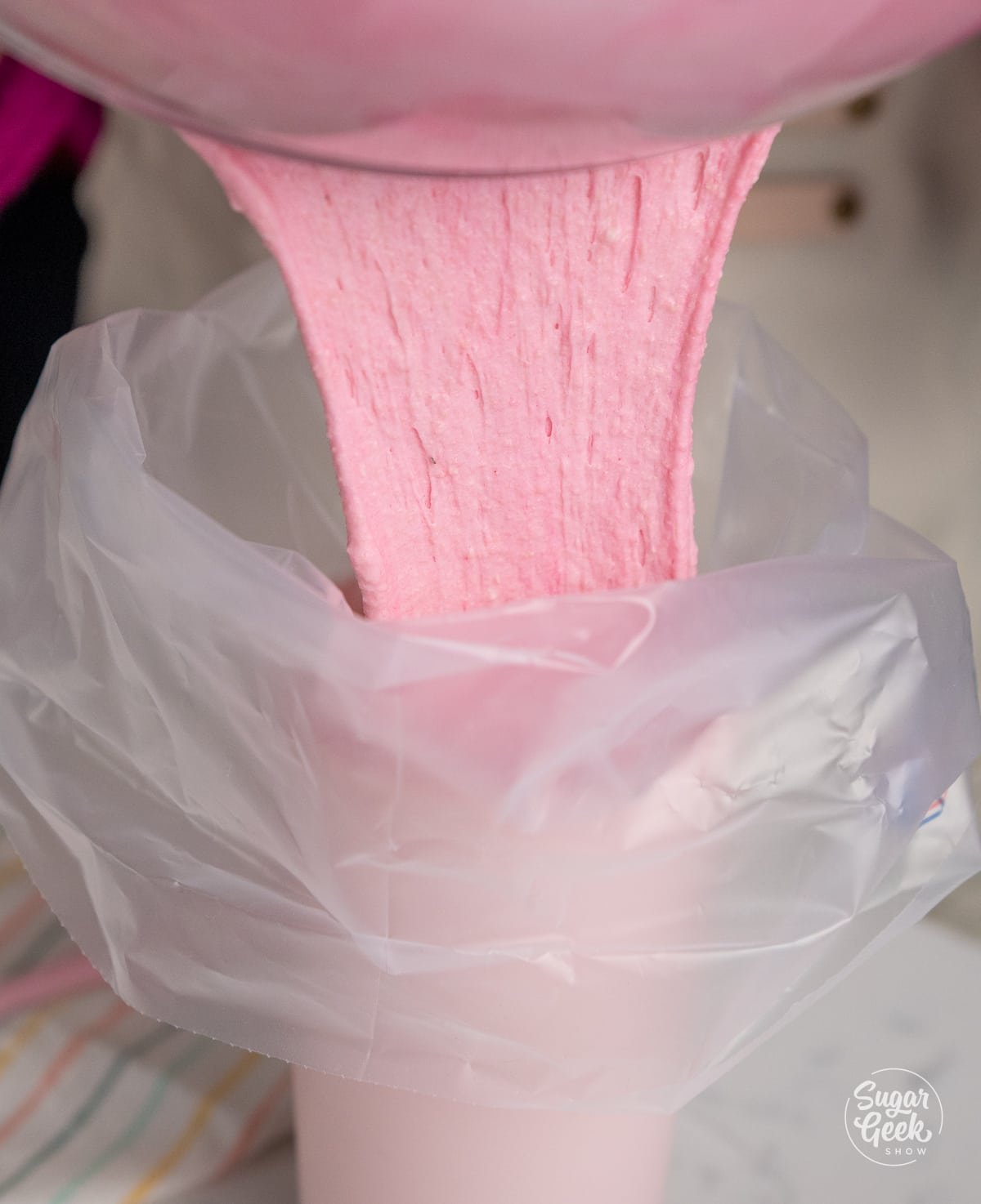 pouring pink macaron batter into a pastry bag