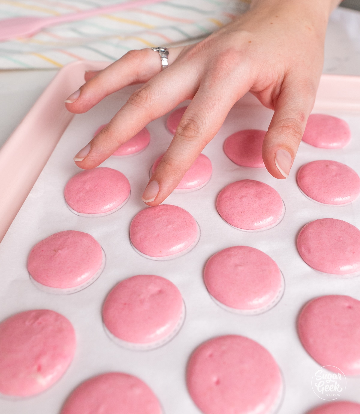 finger touching the top of a rested unbaked macaron