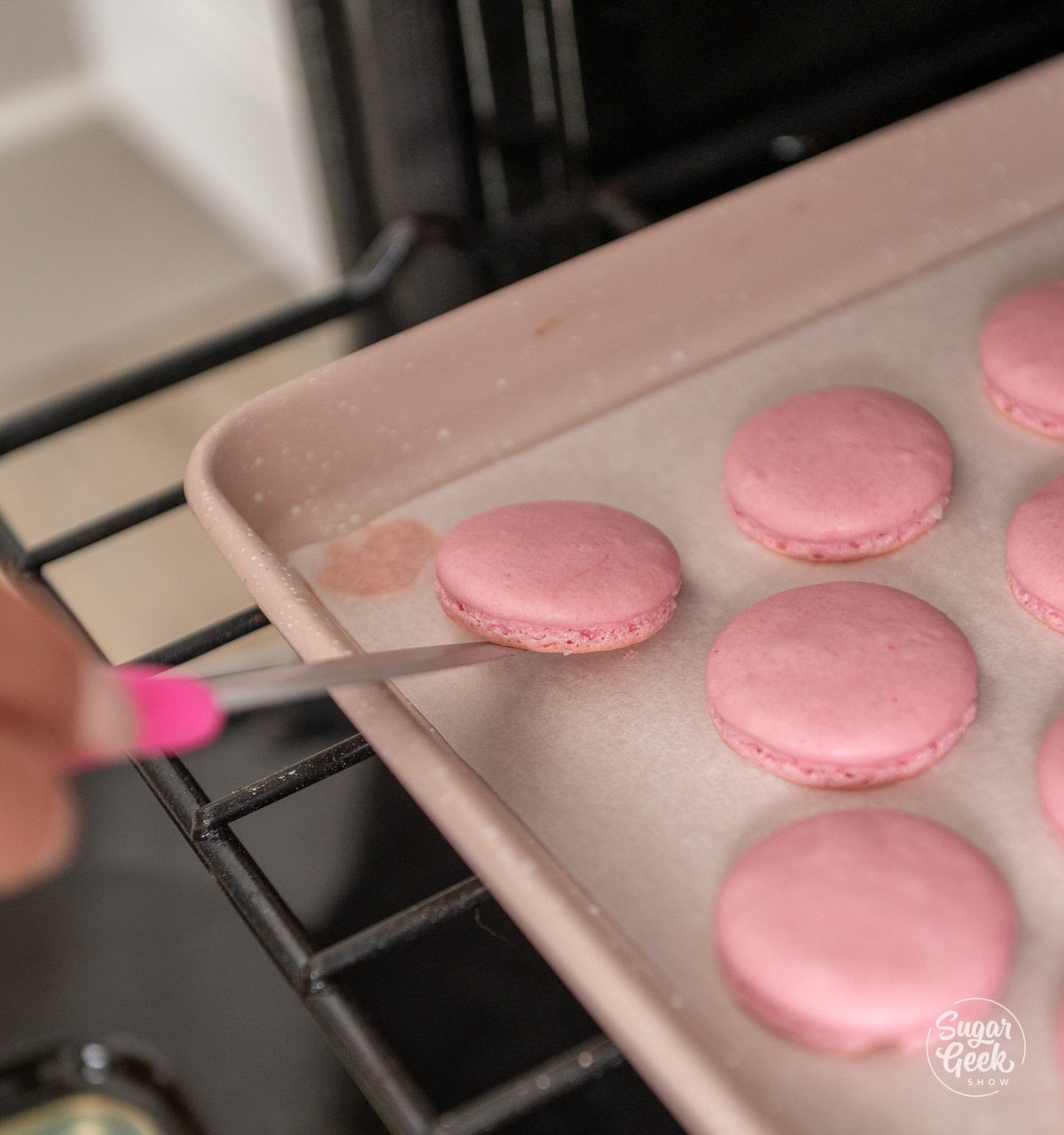 knife lifting a macaron off a baking tray