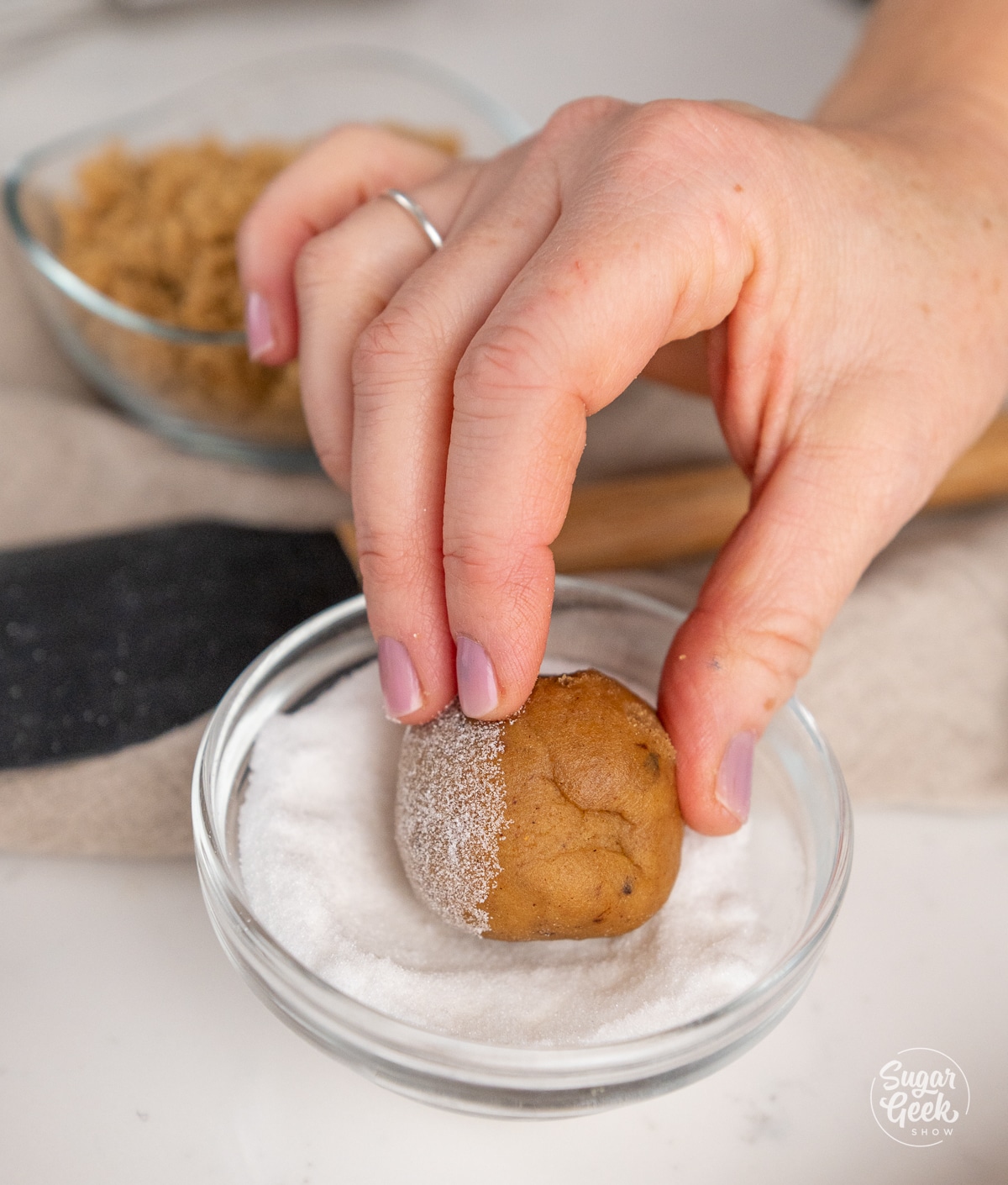 hand rolling a cookie dough ball in sugar