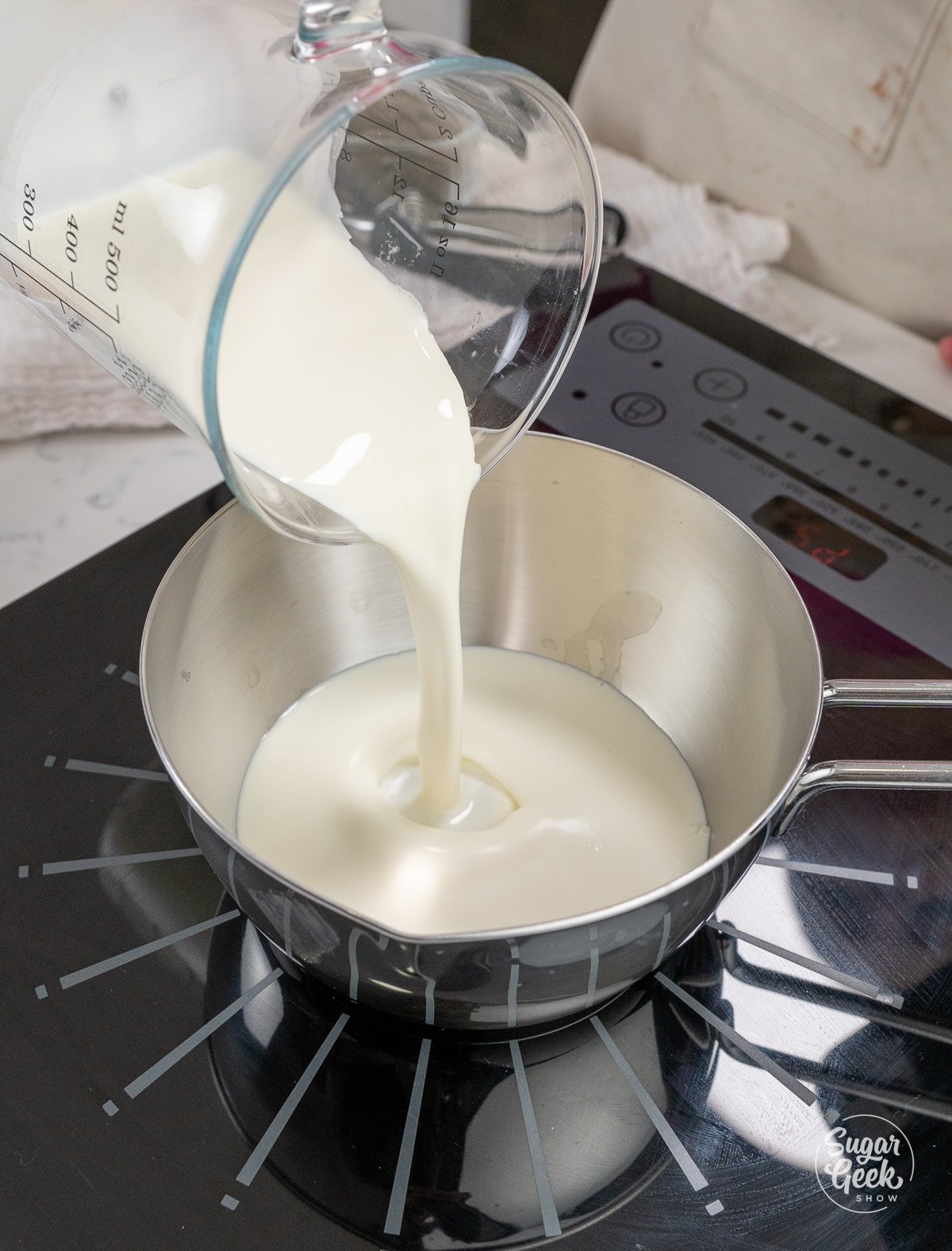 pouring a container of cream into a saucepan