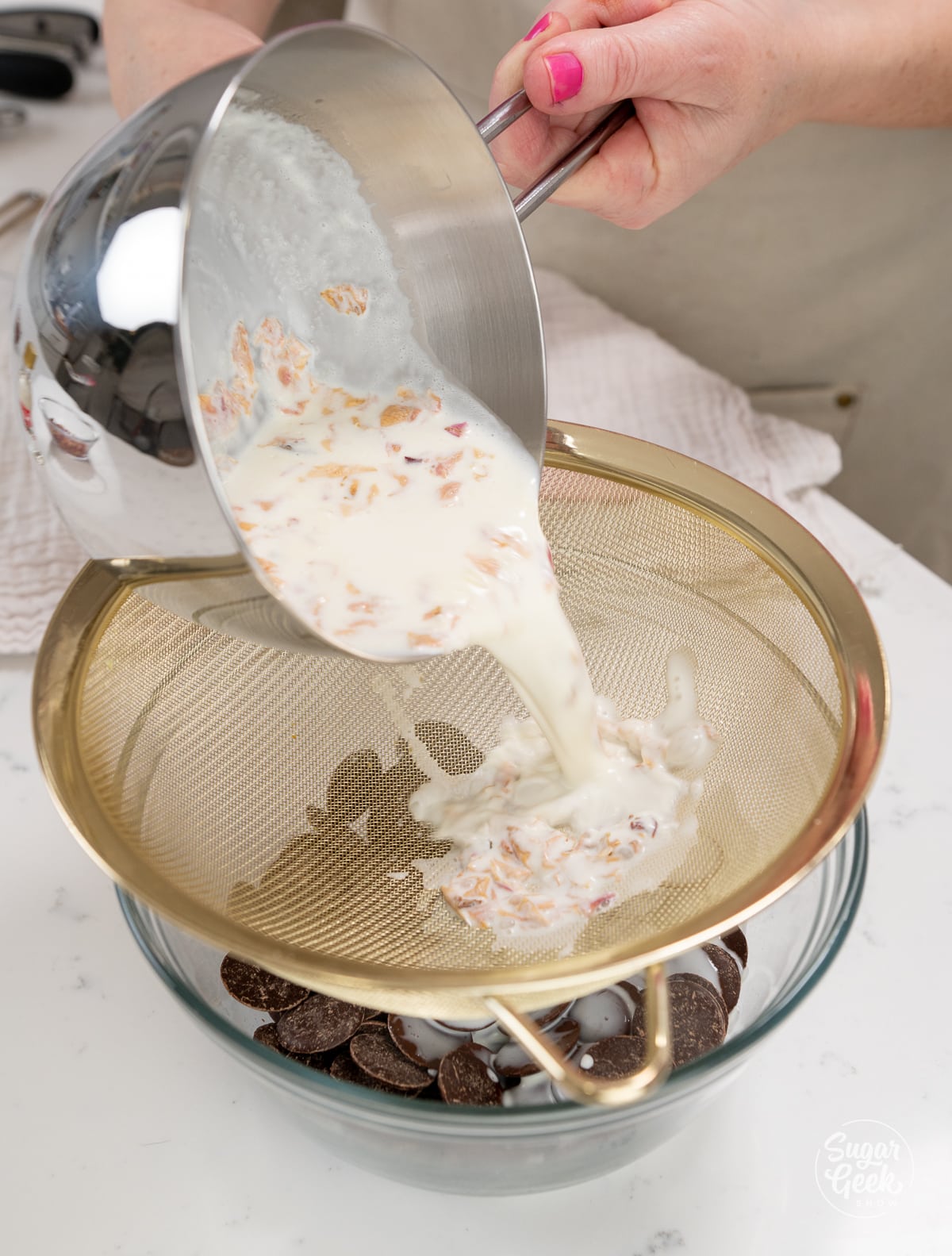 hands pouring rose petal cream over a bowl of chocolate