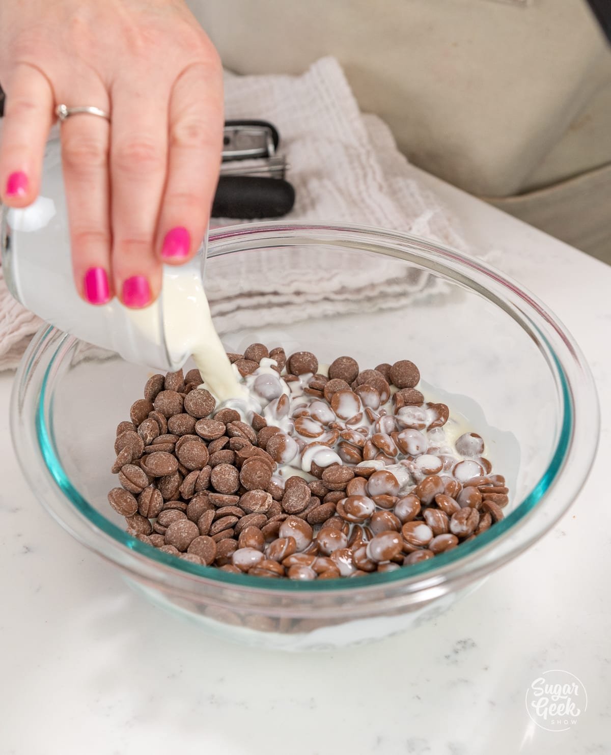 hand adding a bowl of hot cream to milk chocolate