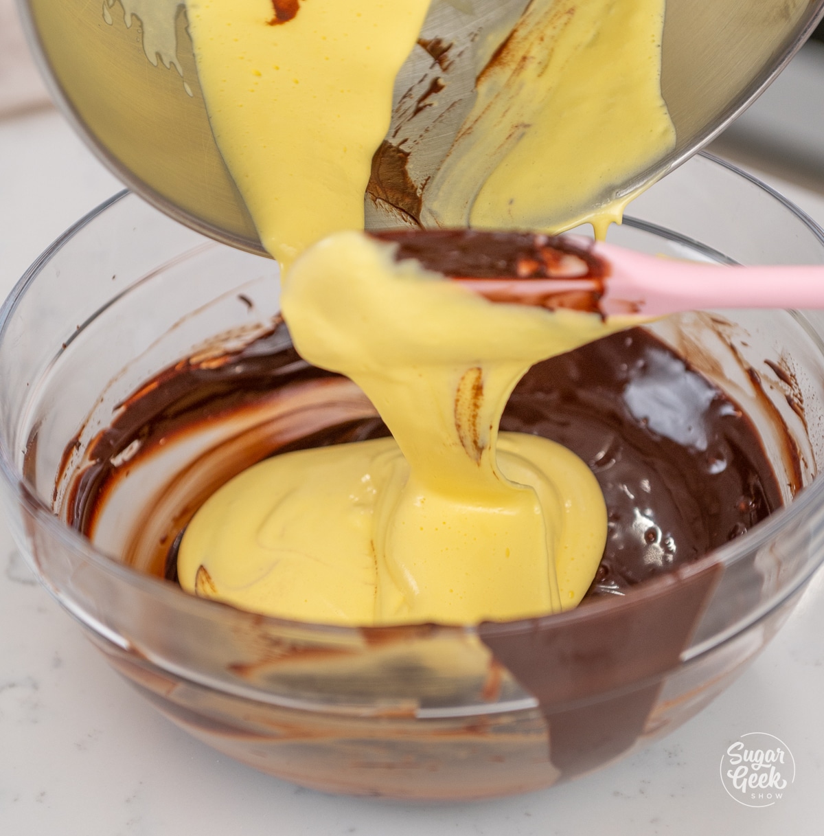 spatula pouring egg yolk mixture into melted chocolate