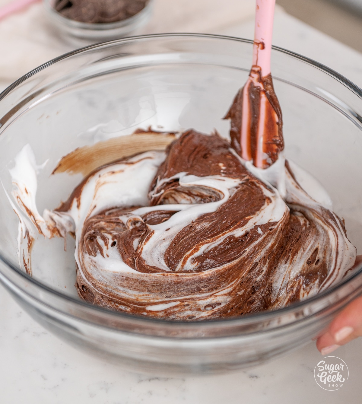 spatula folding egg whites mixture into a bowl of chocolate batter