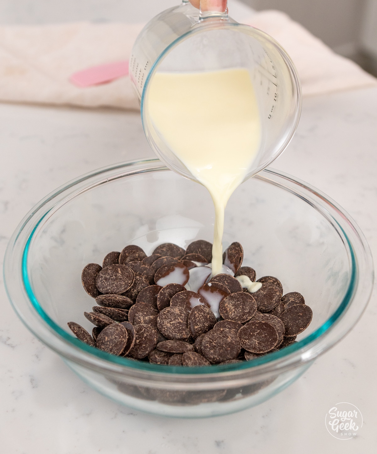 hand adding a bowl of hot cream to dark chocolate