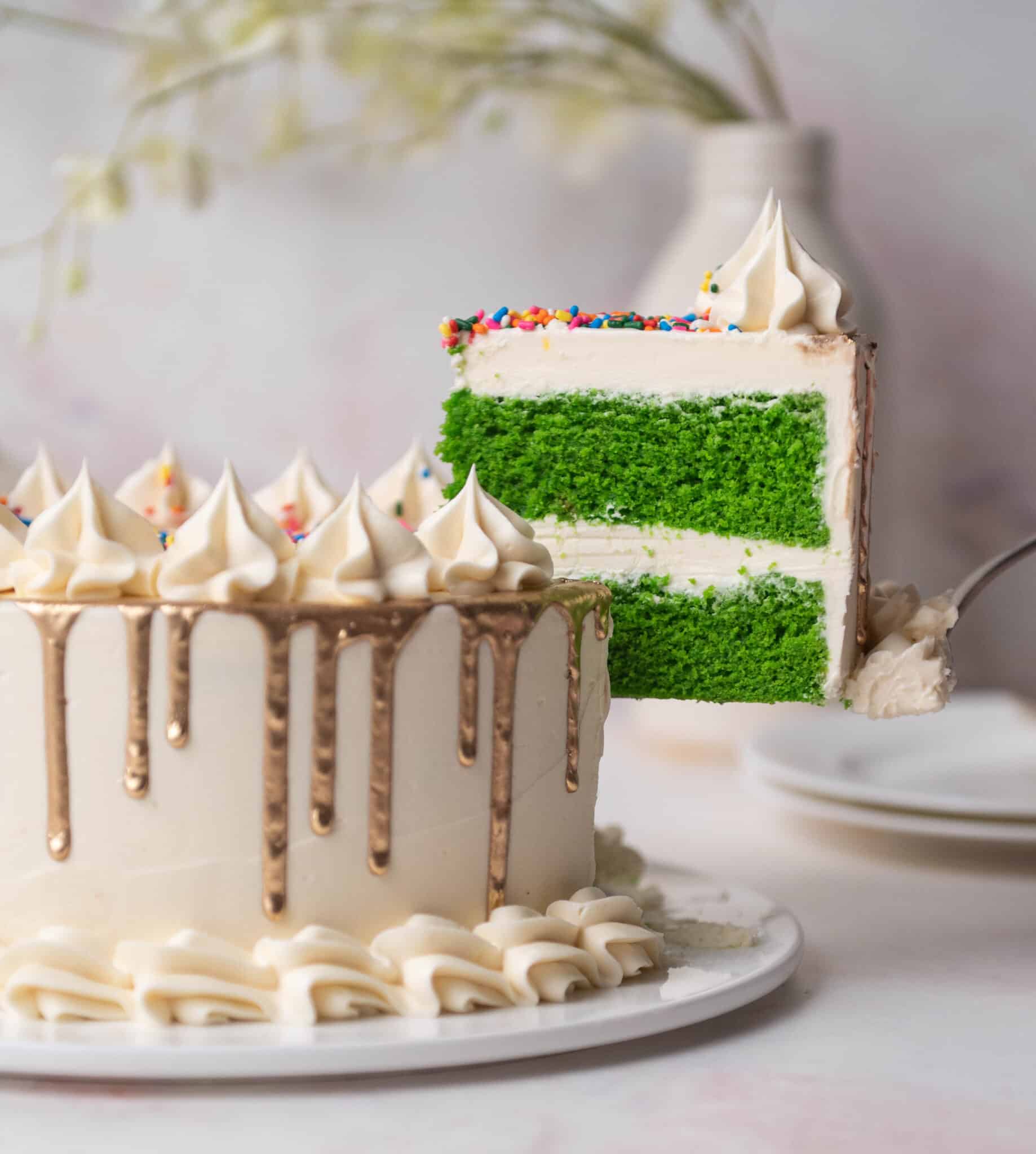 slice of green velvet cake lifting out of a full cake with a cake server