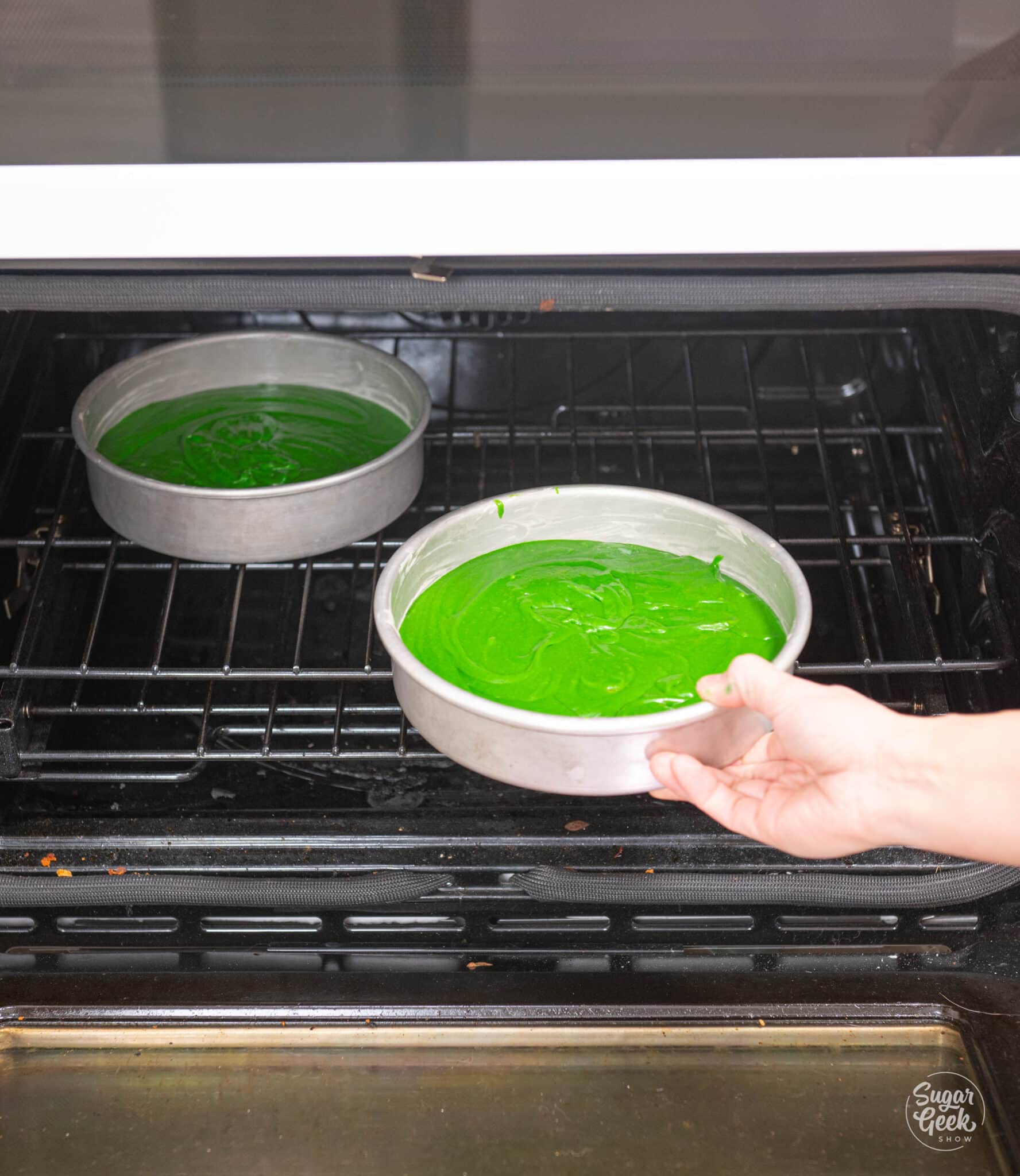 green velvet batter in cake pans in an oven
