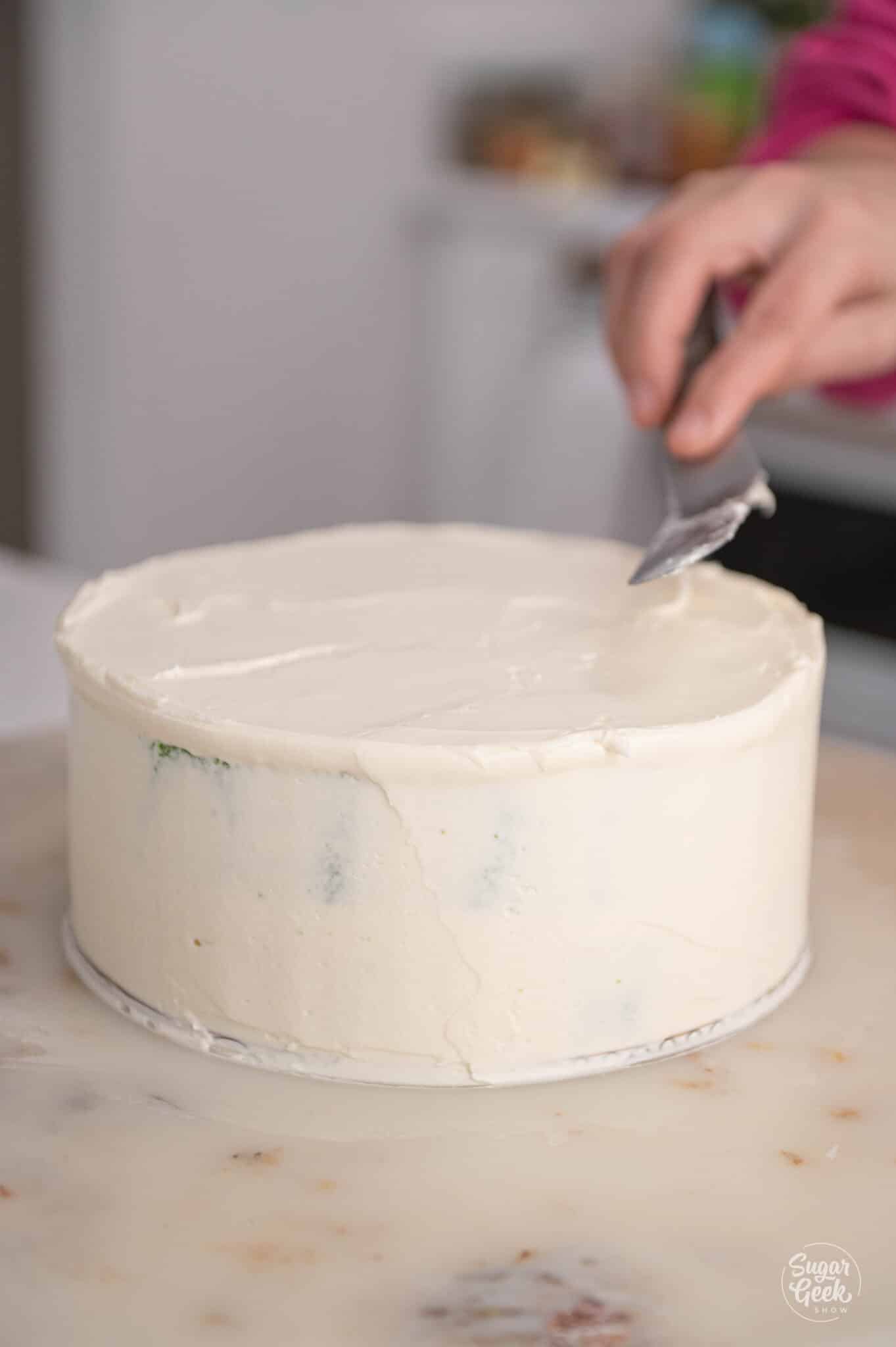 smoothing buttercream on a cake