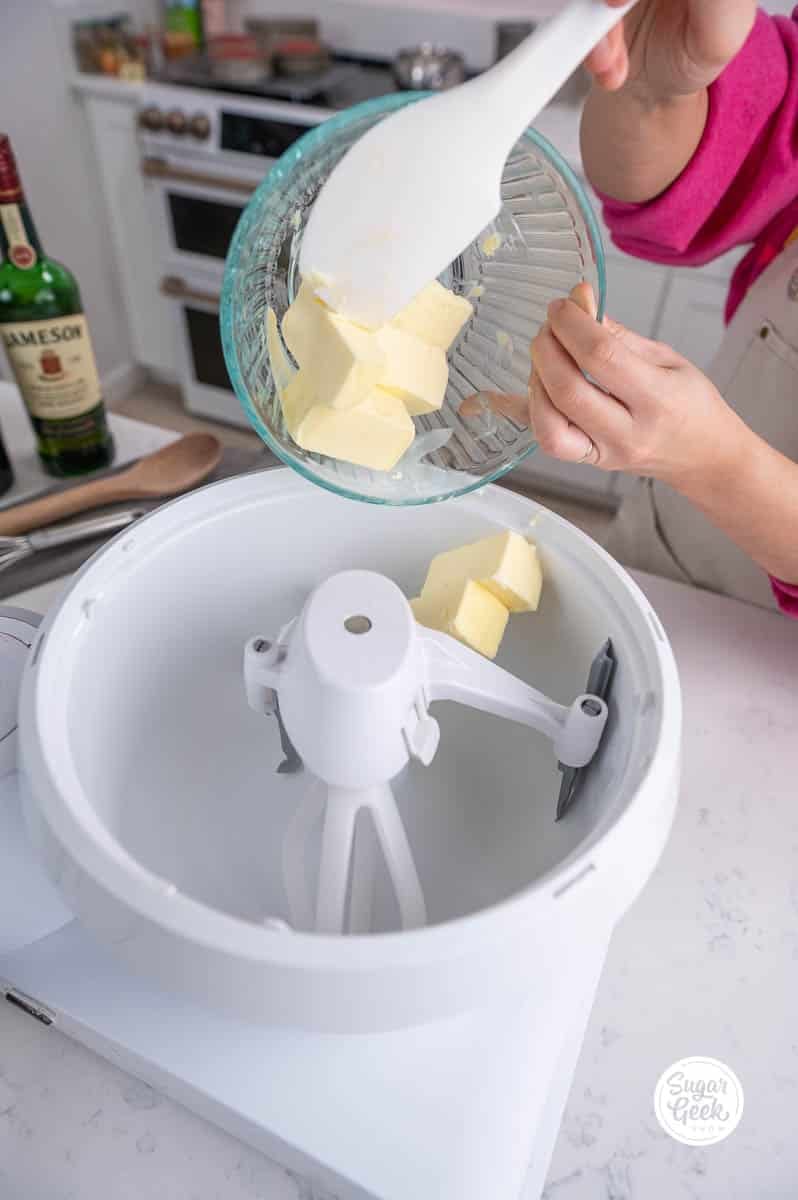 hand adding a bowl of butter into a stand mixer bowl