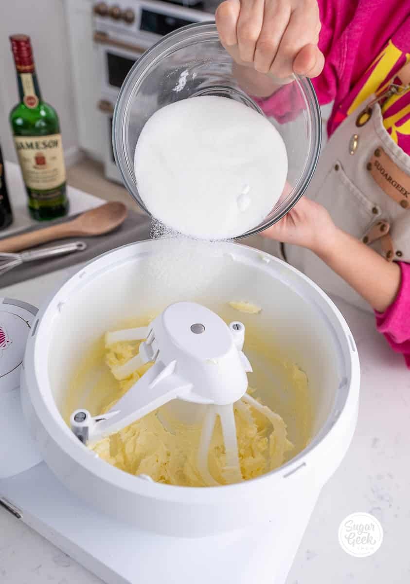 hand adding a bowl of sugar into a stand mixer bowl