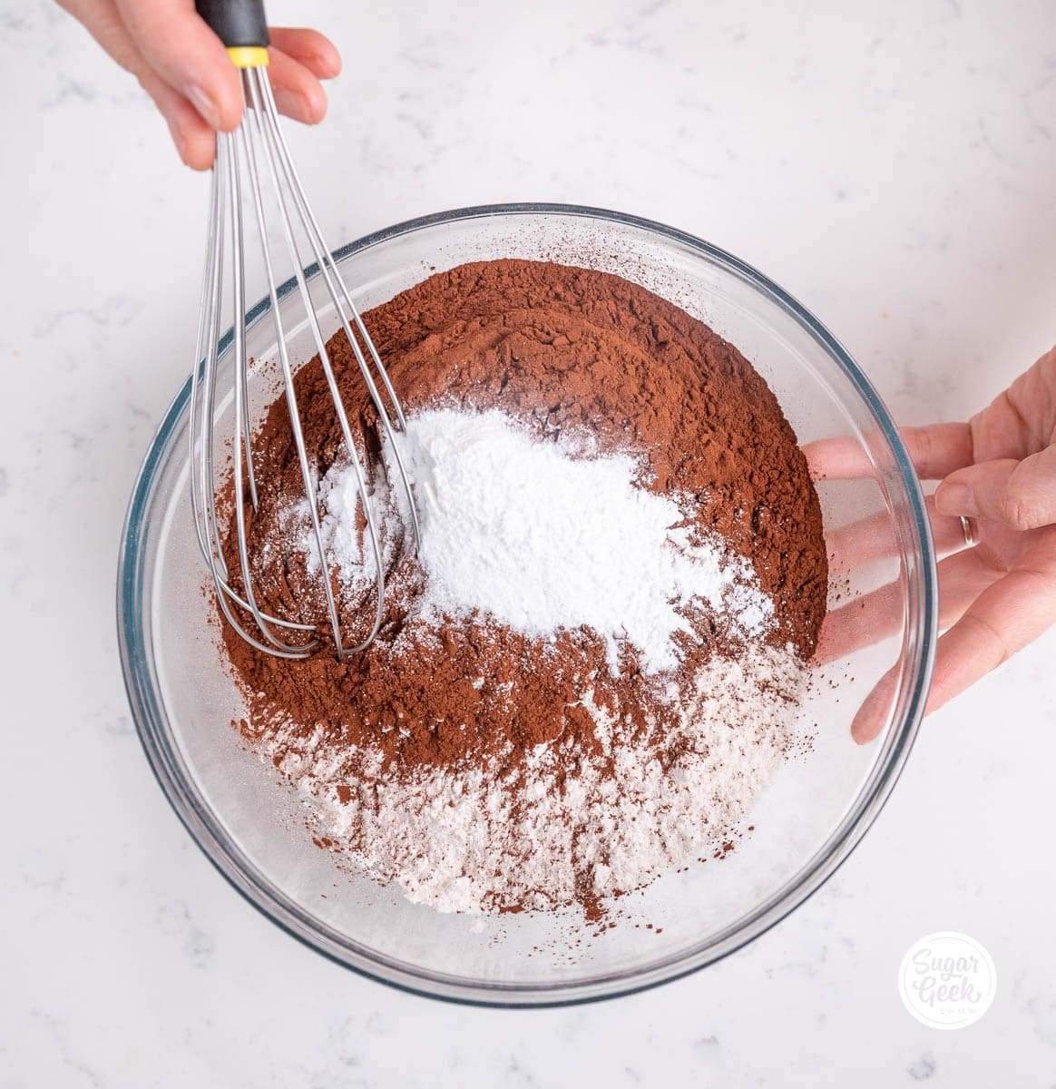 hands whisking a bowl of chocolate cake ingredients