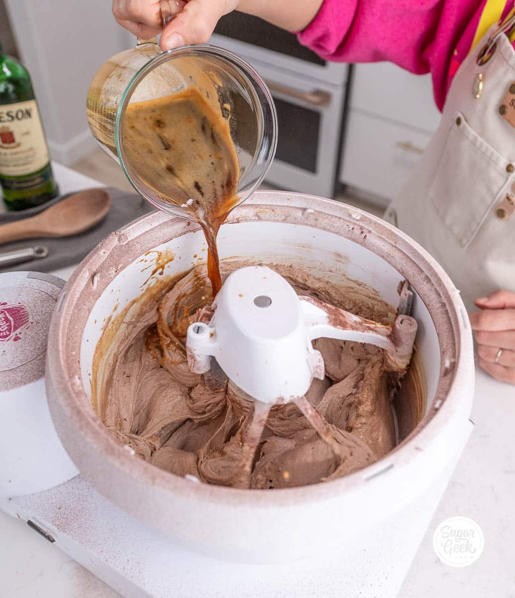 hand pouring liquid ingredients from a measuring cup into a stand mixer bowl