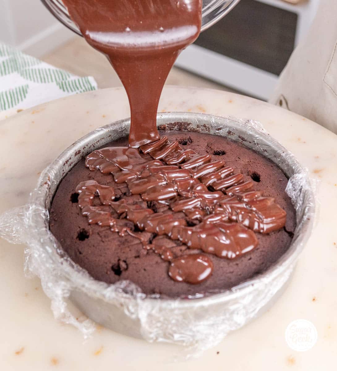 drizzling chocolate sauce into the holes of a chocolate cake