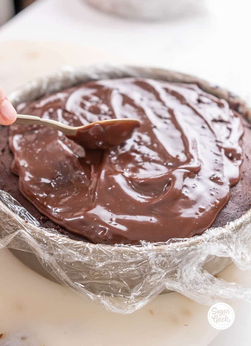 hand smoothing out the chocolate glaze with a spoon