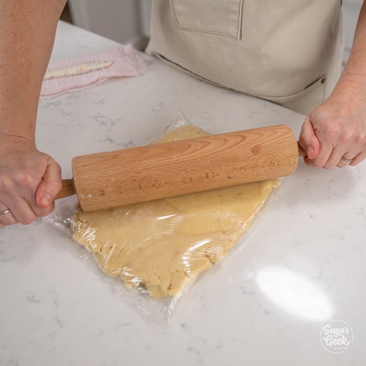 hand using rolling pin to roll dough into sqaure.