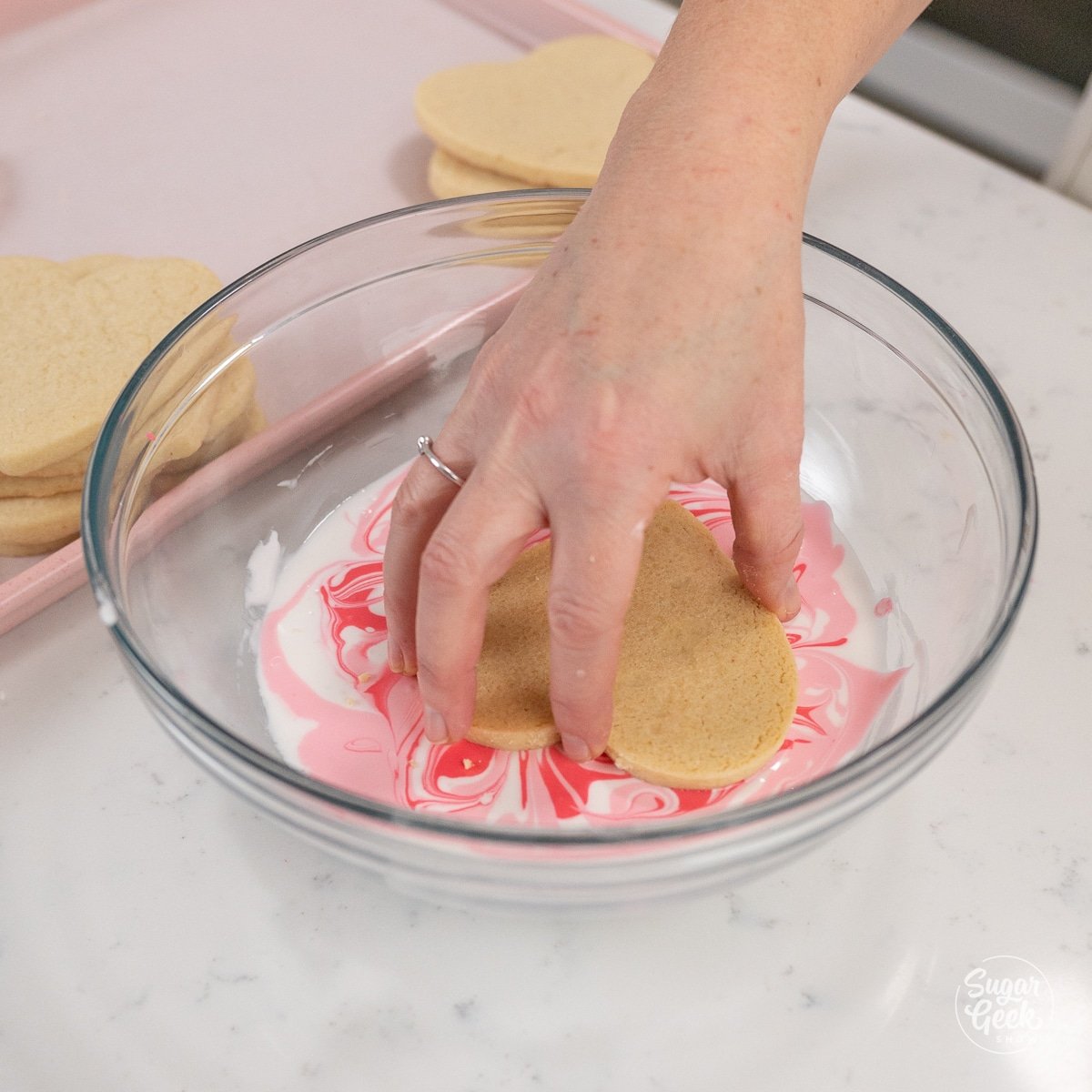 hand dipping cookie into royal icing.