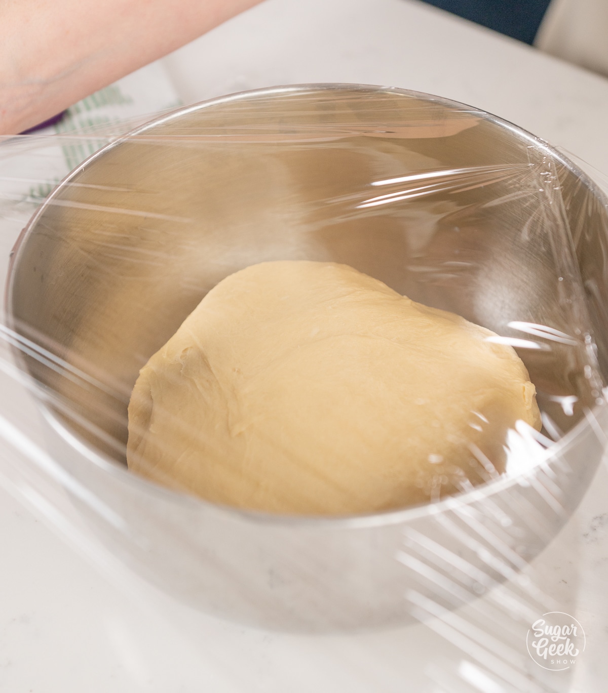 dough in a metal bowl covered with plastic