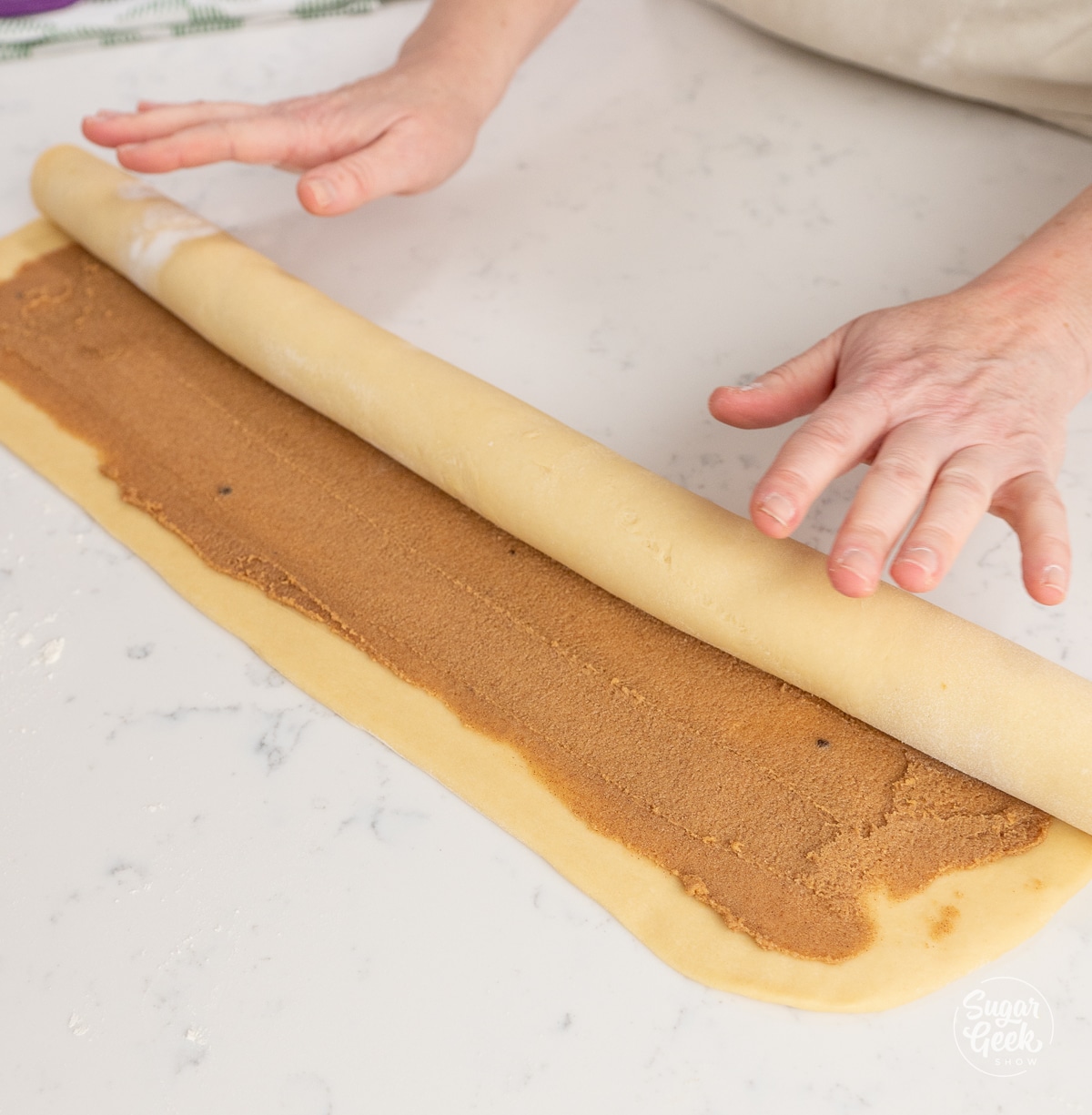 hands rolling dough with cinnamon filling