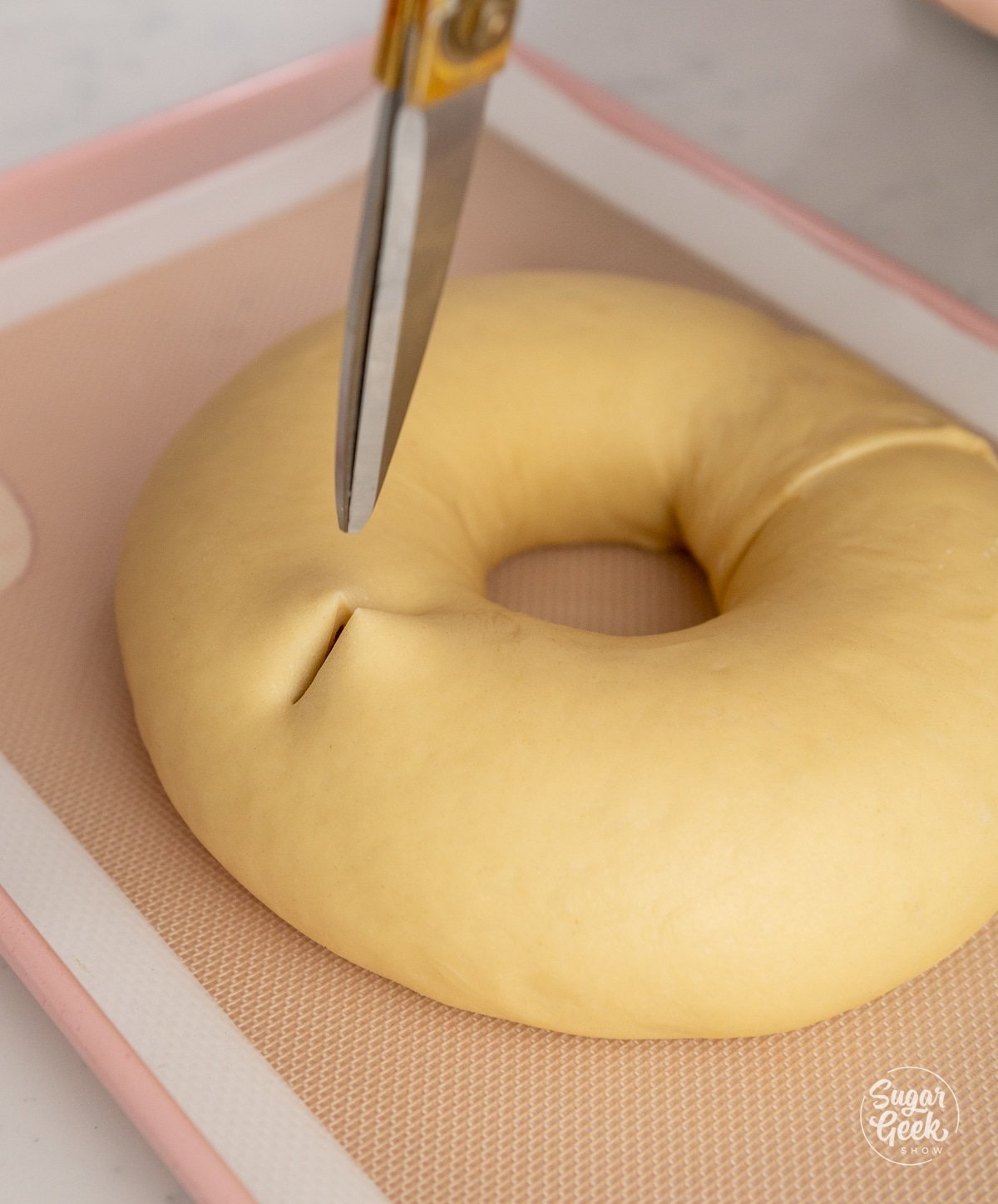 scissors cutting slits in a ring of dough