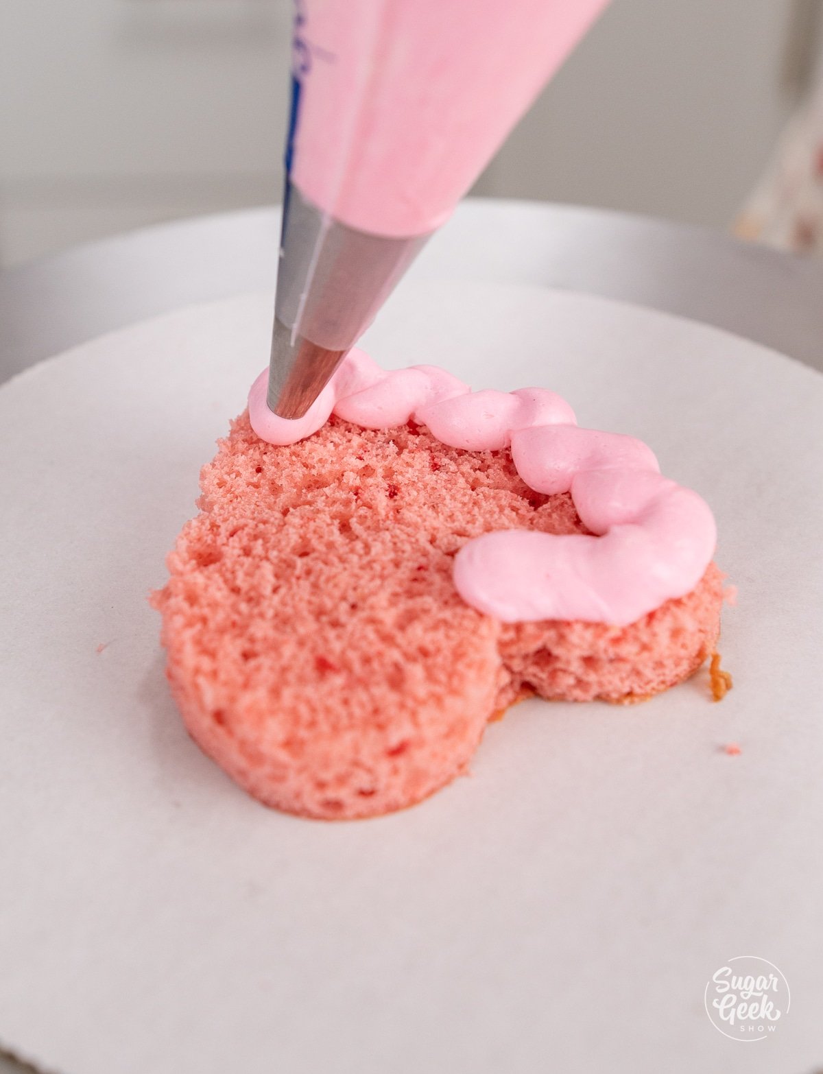 piping bag making a dam of buttercream on a heart cake