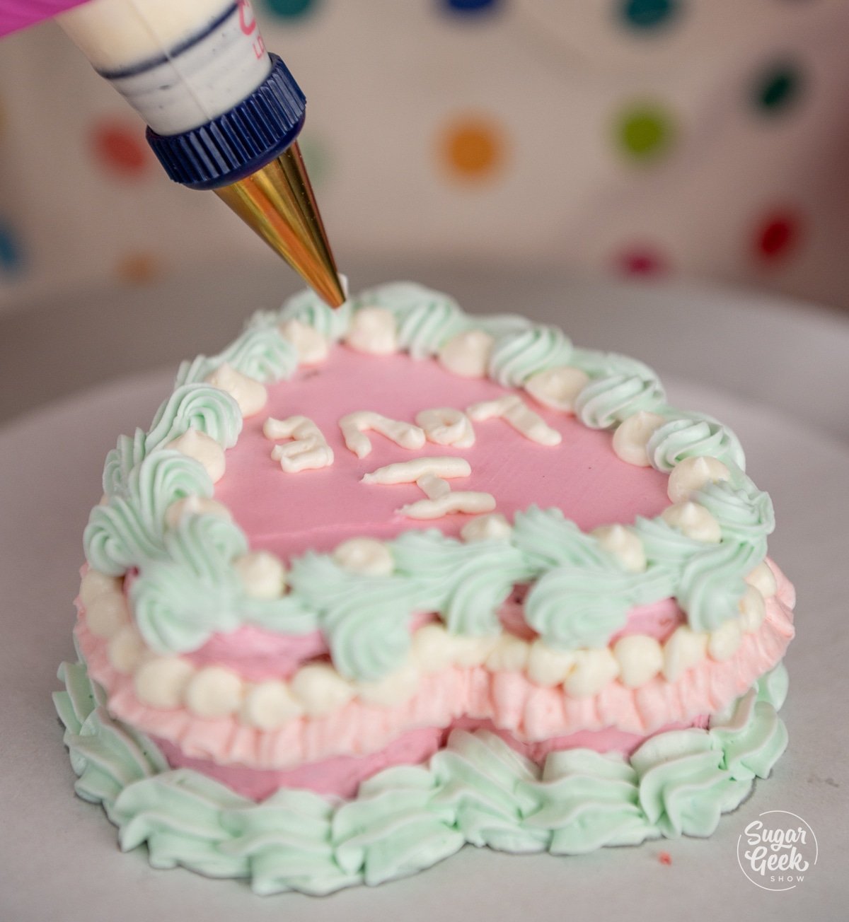 piping bag writing words on top of a heart cake