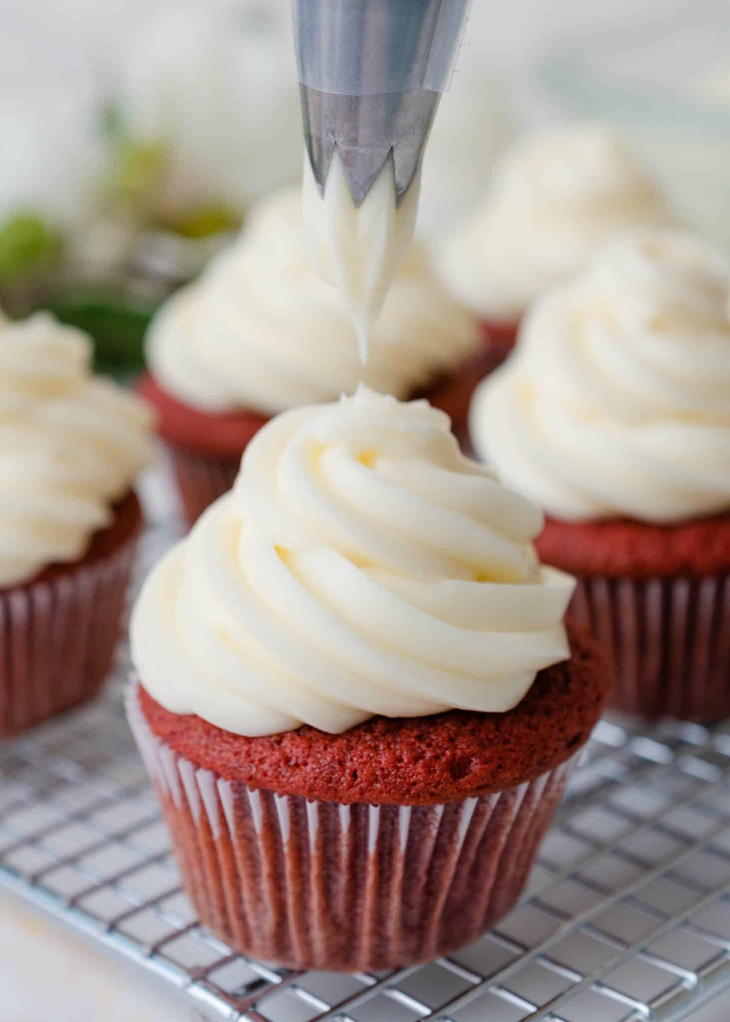 piping tip held above a red velvet cupcake
