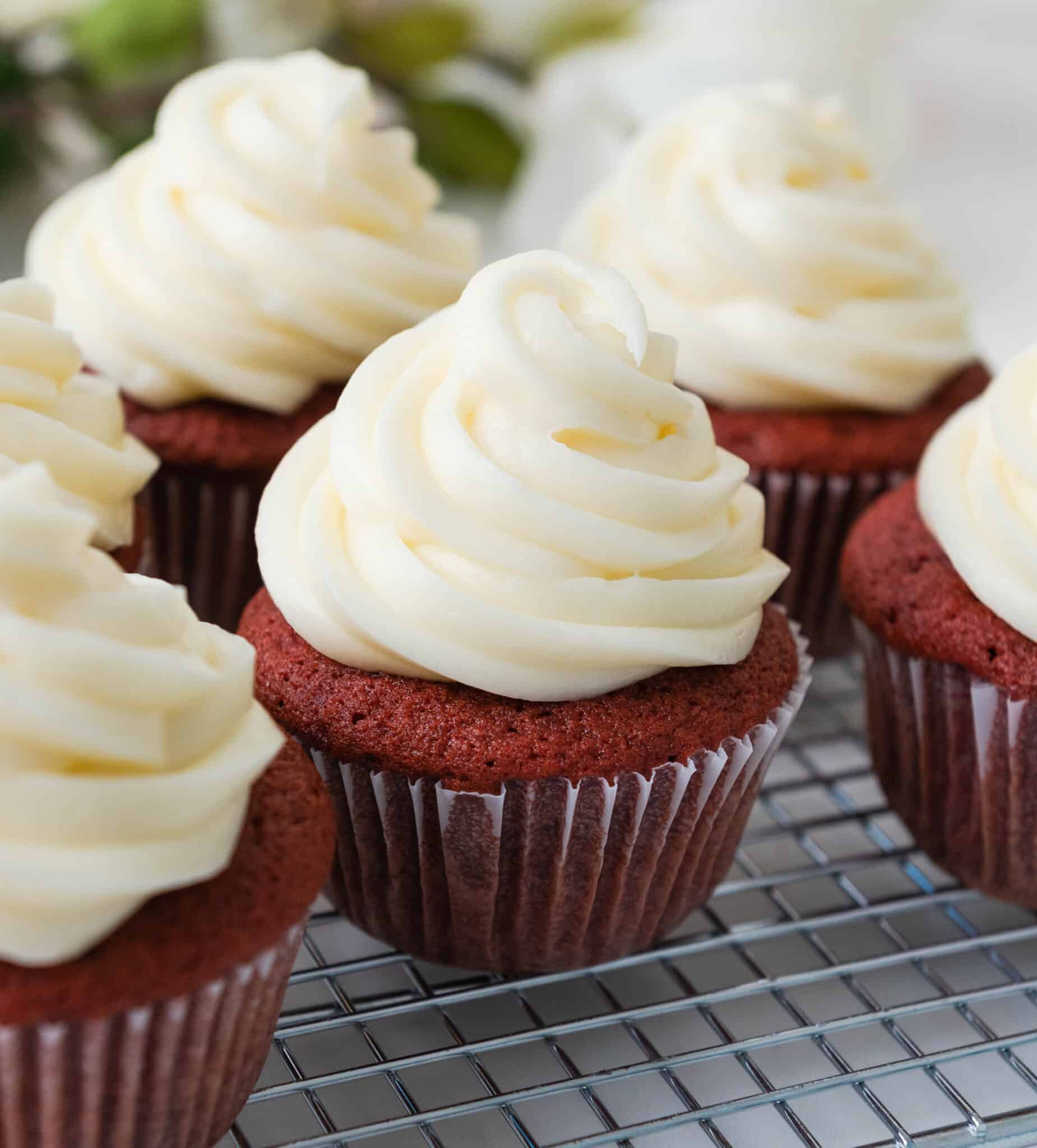 a cluster of red velvet cupcakes with swirls of cream cheese frosting on top