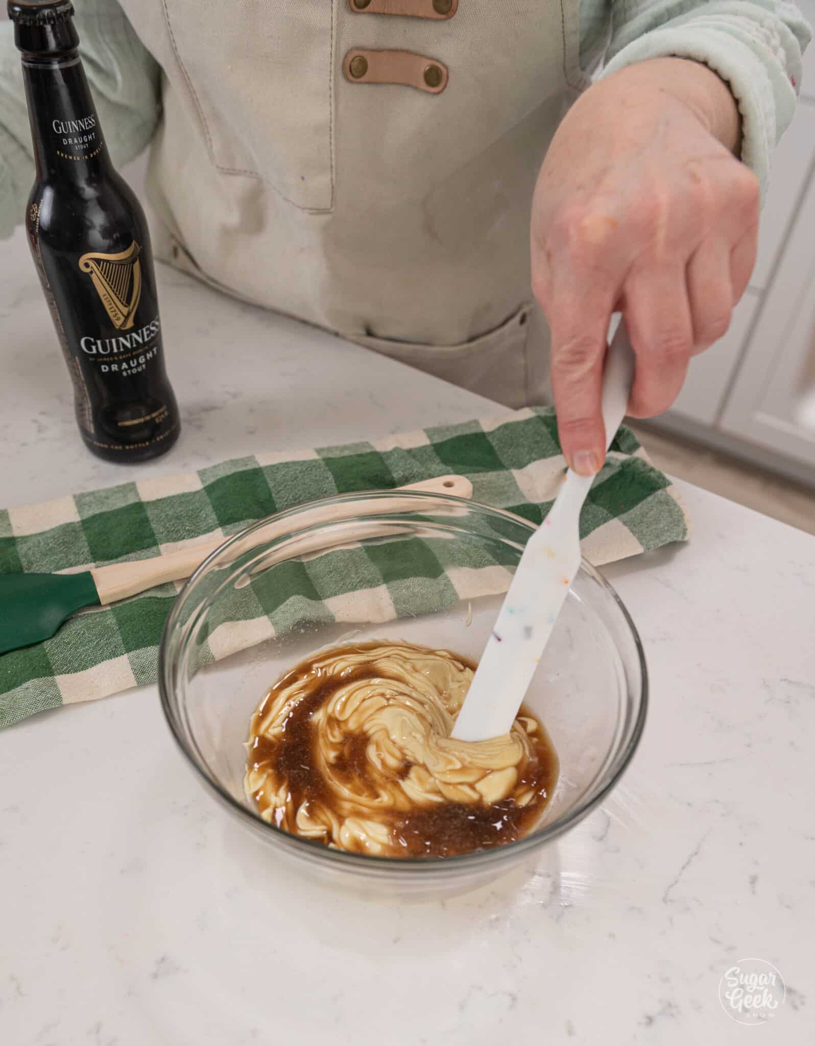 mixing together beer and melted chocolate in a bowl with a spatula